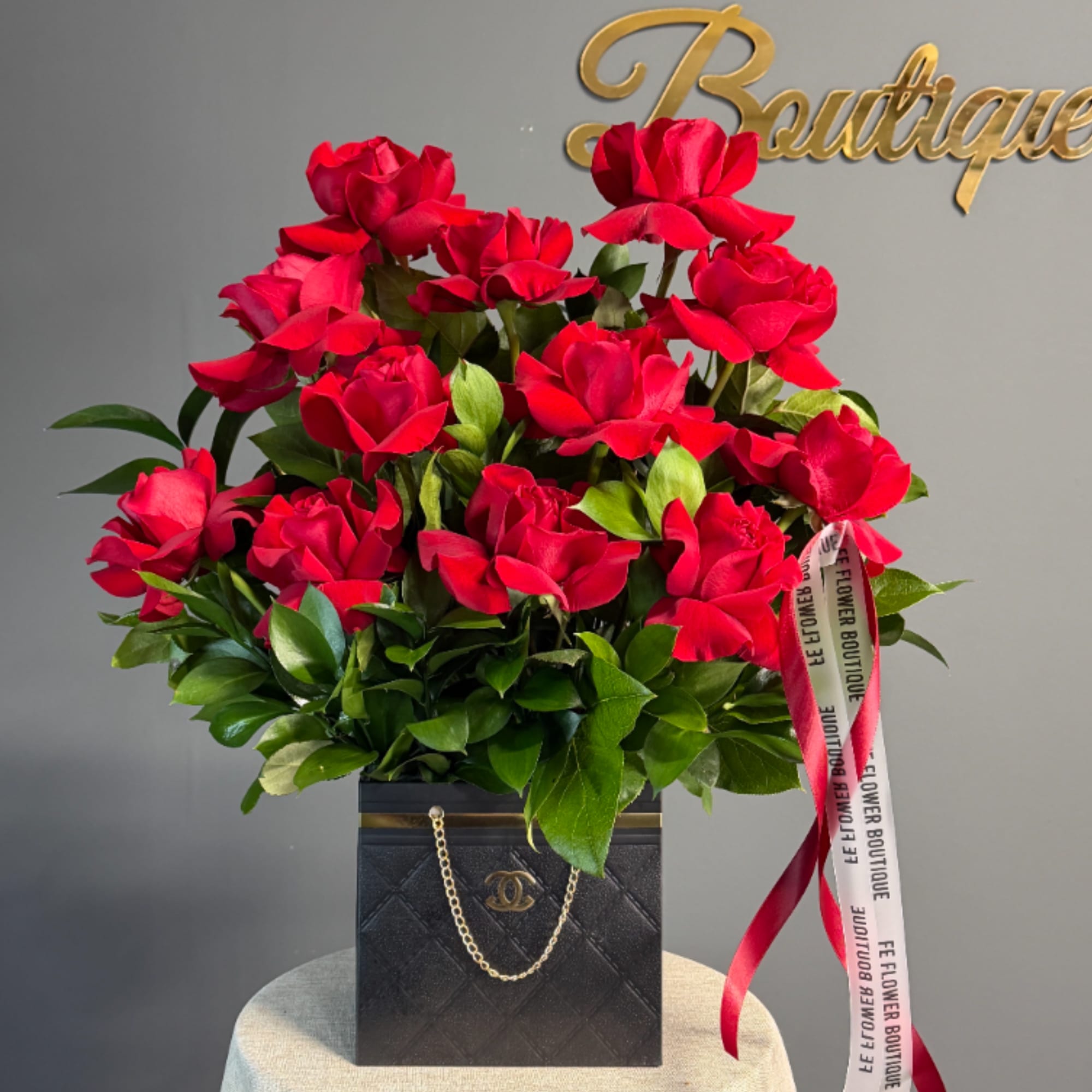 Red rose arrangement in a black box with ribbon accents