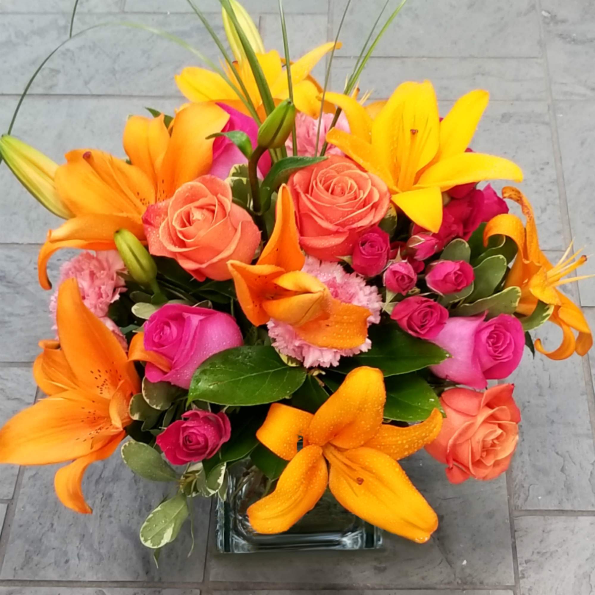 Bright bouquet of orange lilies and pink roses in a glass vase, photo 2 of 2
