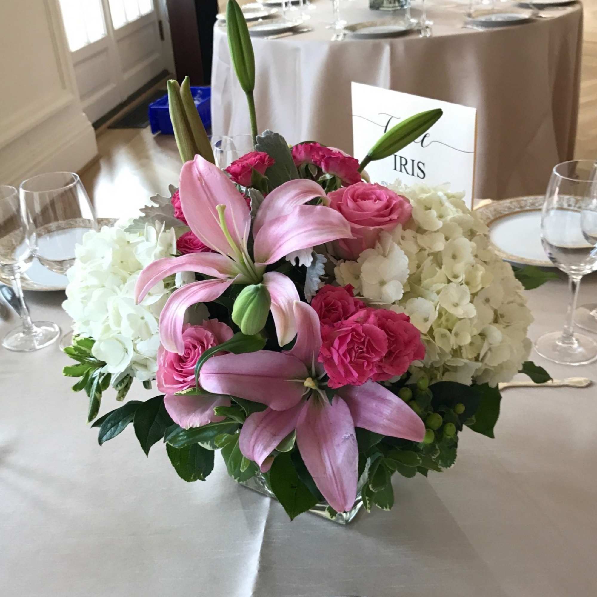 Pink lilies and roses in a low glass centerpiece with white hydrangeas
