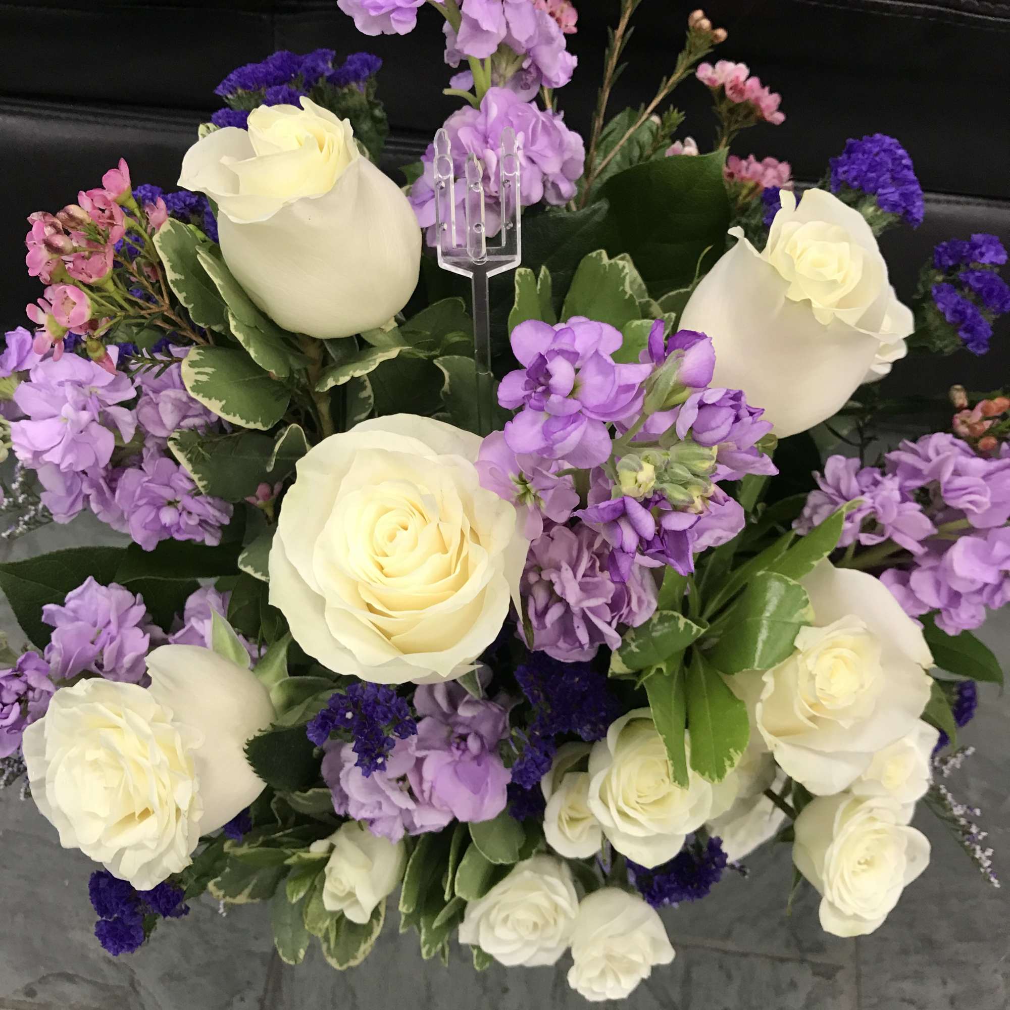 Bouquet of white roses and purple flowers with greenery