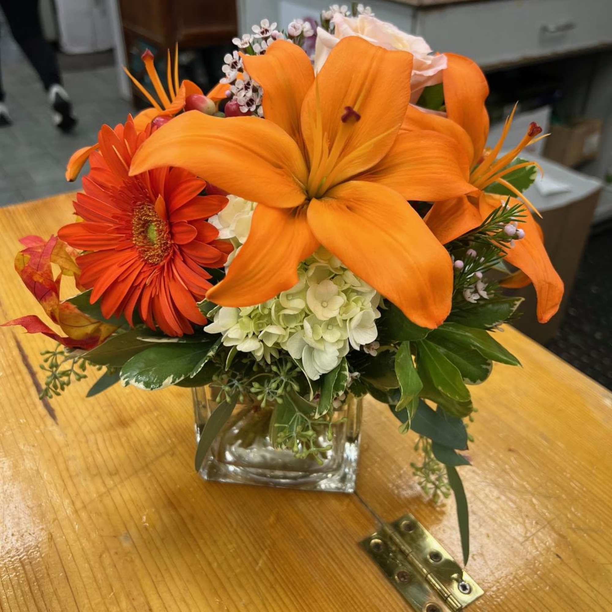 Orange lilies and gerbera daisies in a square glass vase