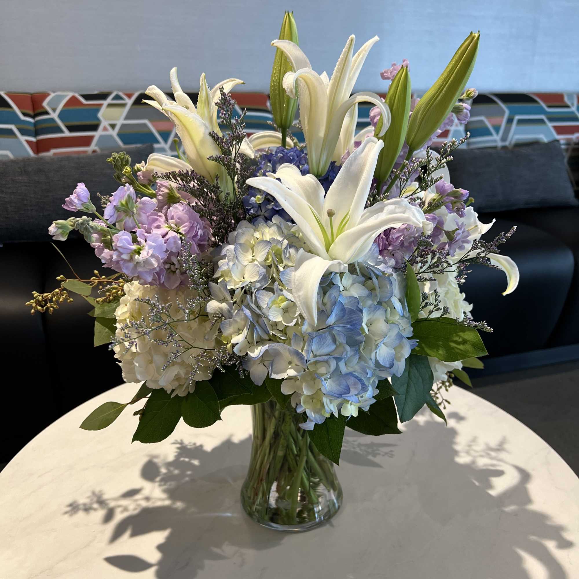 Bouquet of white lilies and blue hydrangeas in a glass vase