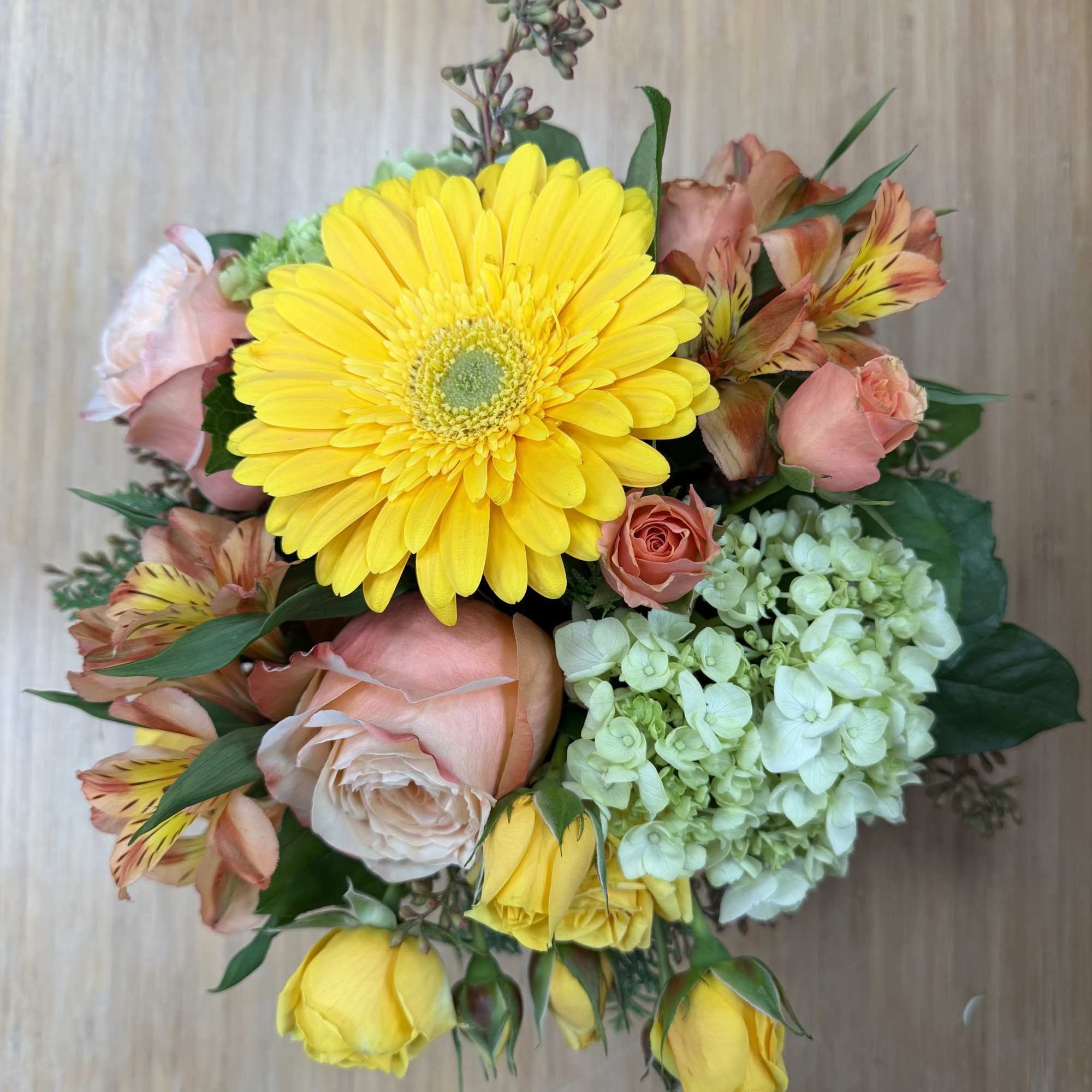 Bouquet with a yellow gerbera daisy, pink roses, and pale green hydrangea