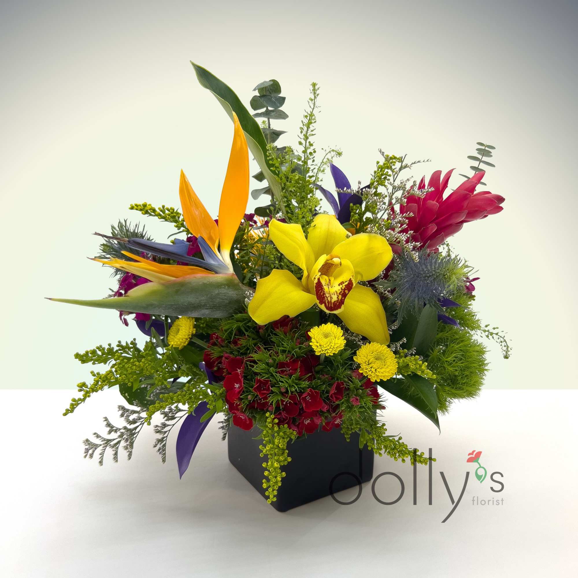 A lush centerpiece held in a small cube vase.