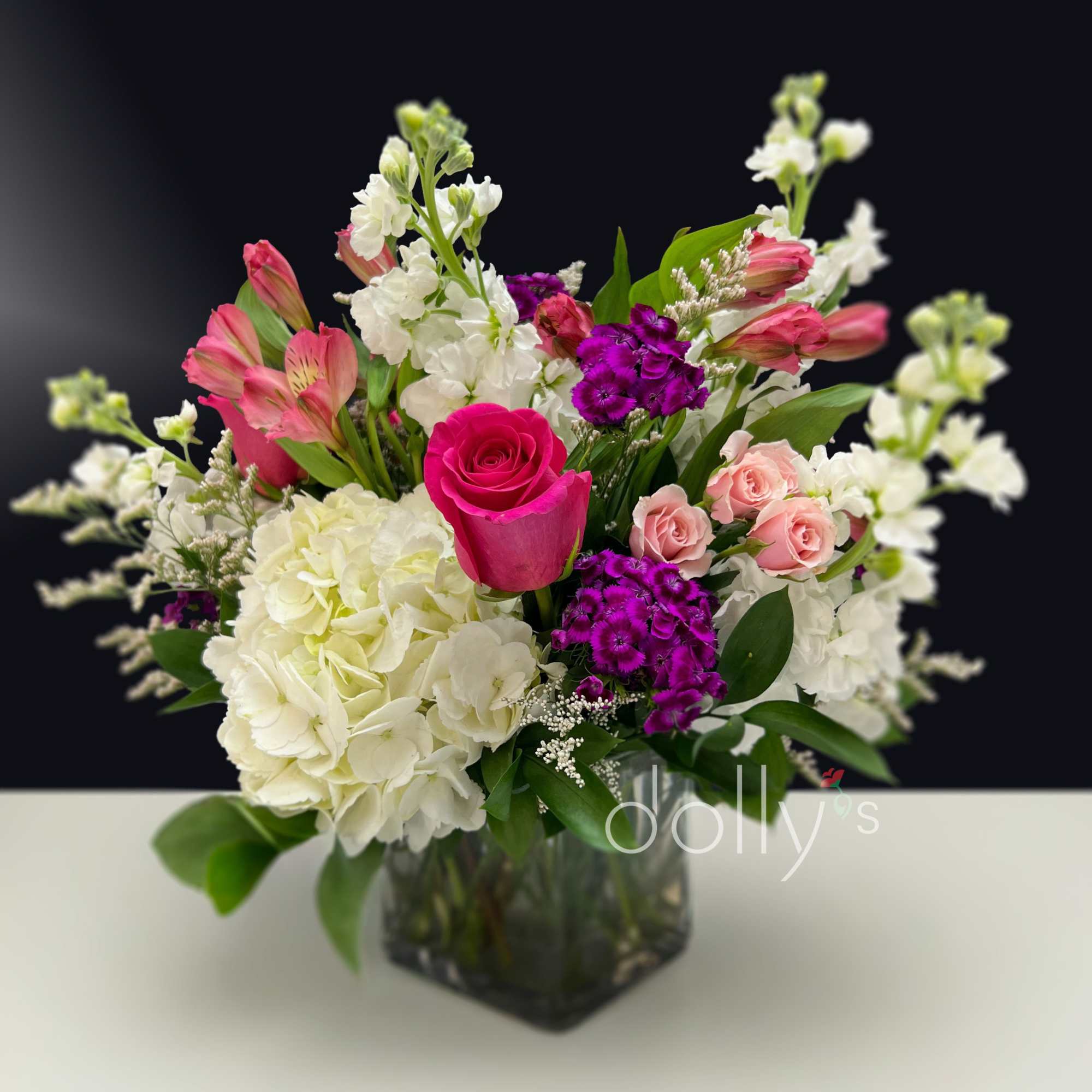 Mixed bouquet in a clear square vase with pink and white flowers