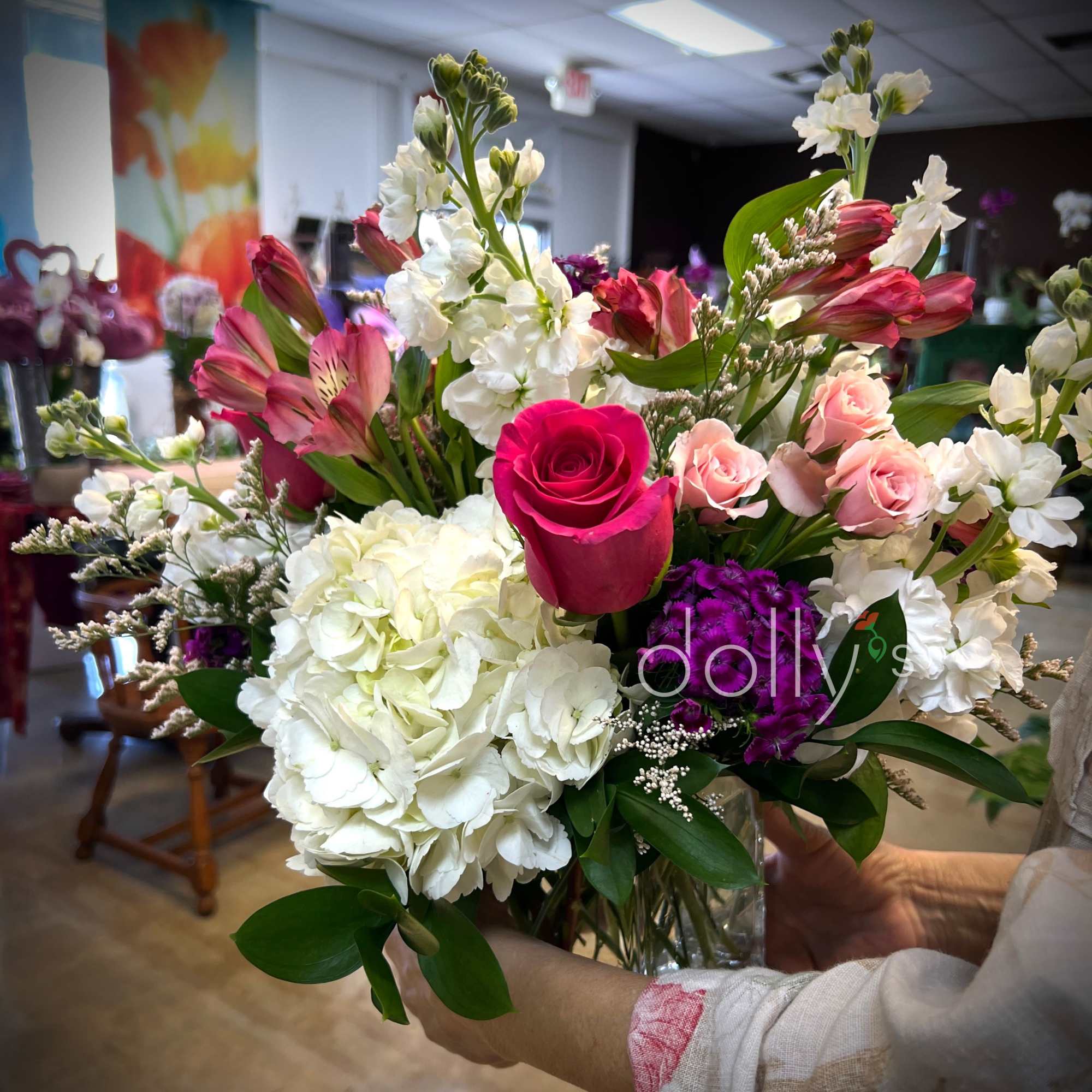 A bright hot-pink rose anchors this lively flower arrangement, surrounded by cloud-like