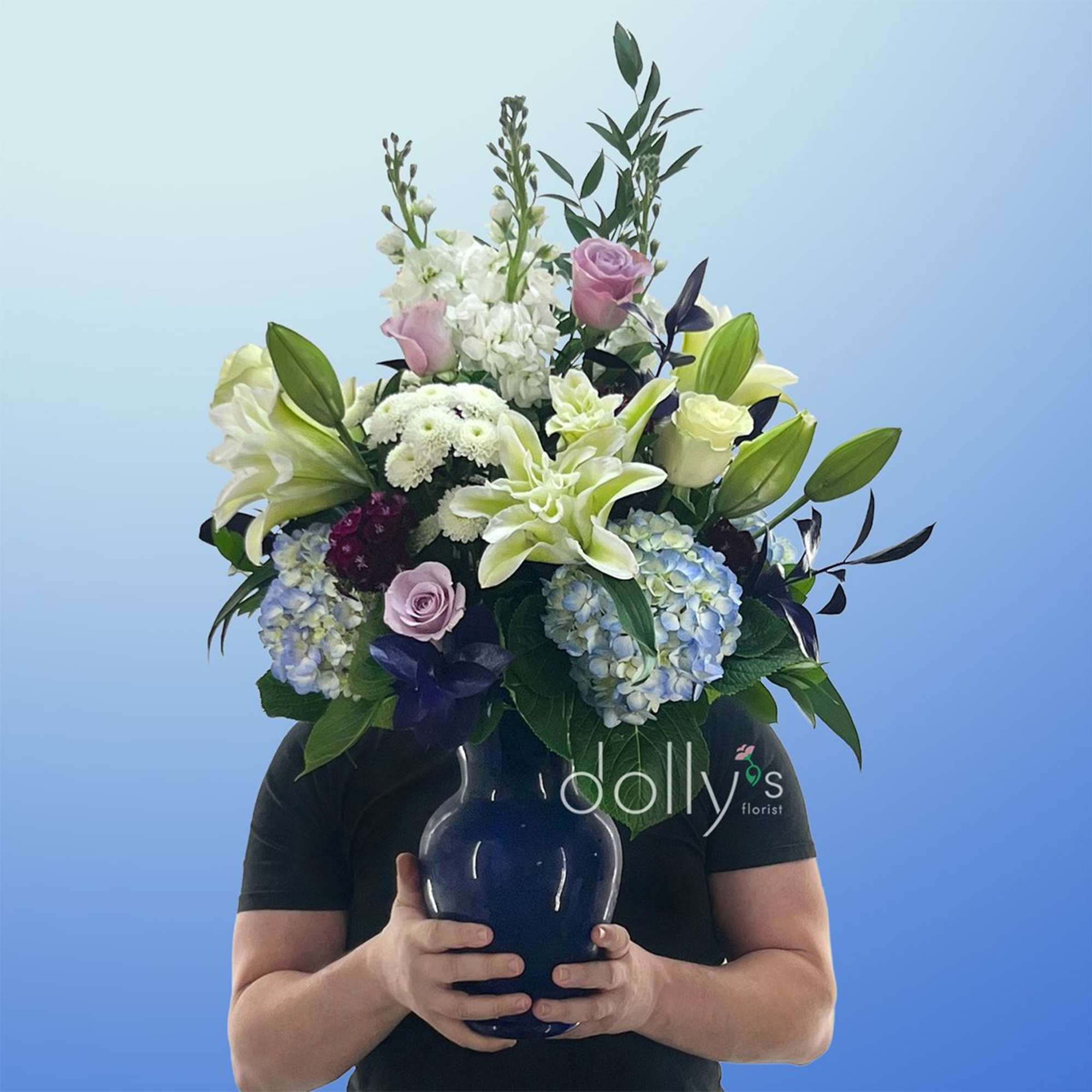 Pale blue hydrangeas and large white lilies create a serene, elegant centerpiece