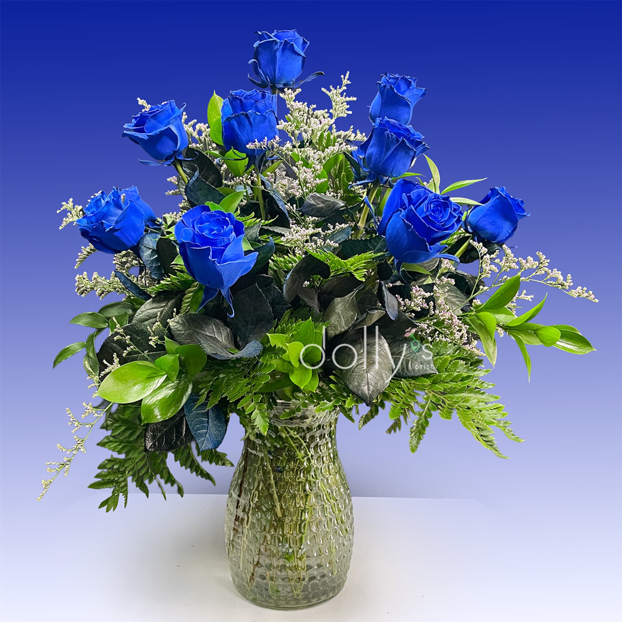 Blue roses arranged in a textured glass vase with greenery
