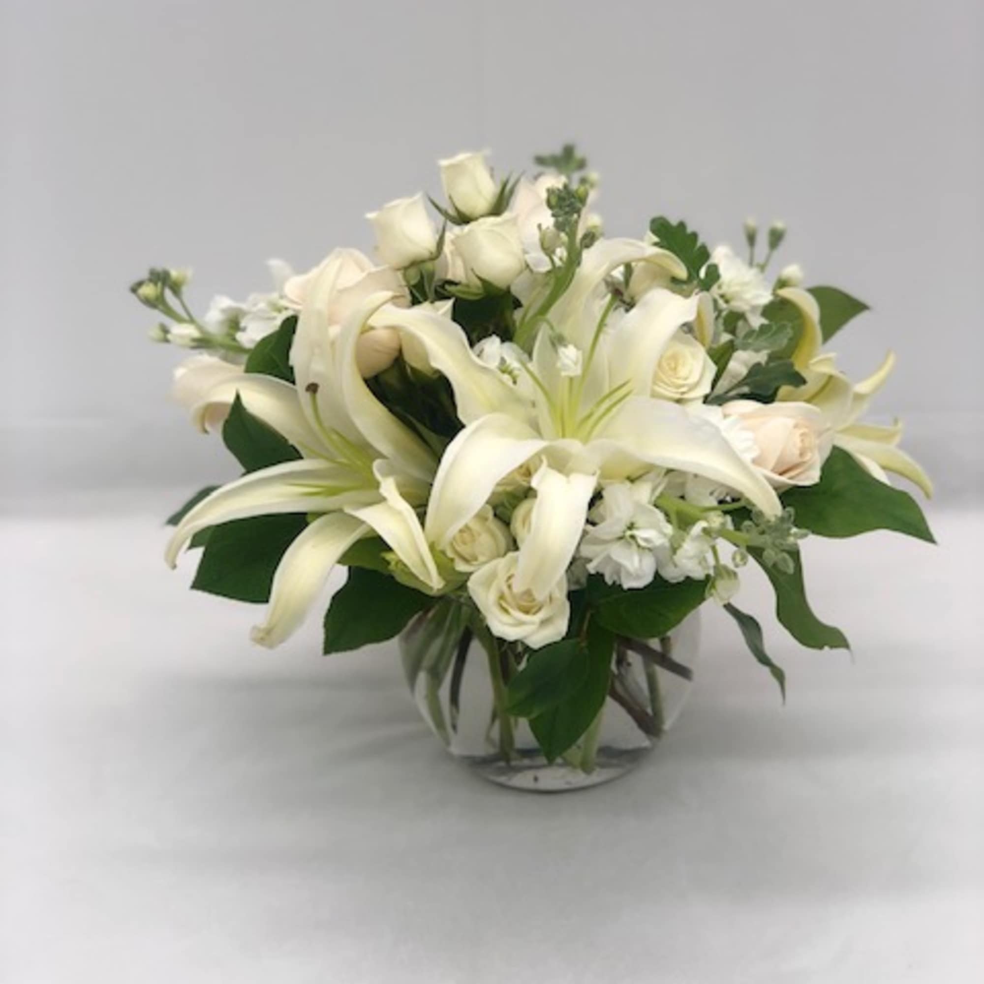 White lilies and roses arranged in a clear glass vase, photo 3 of 3