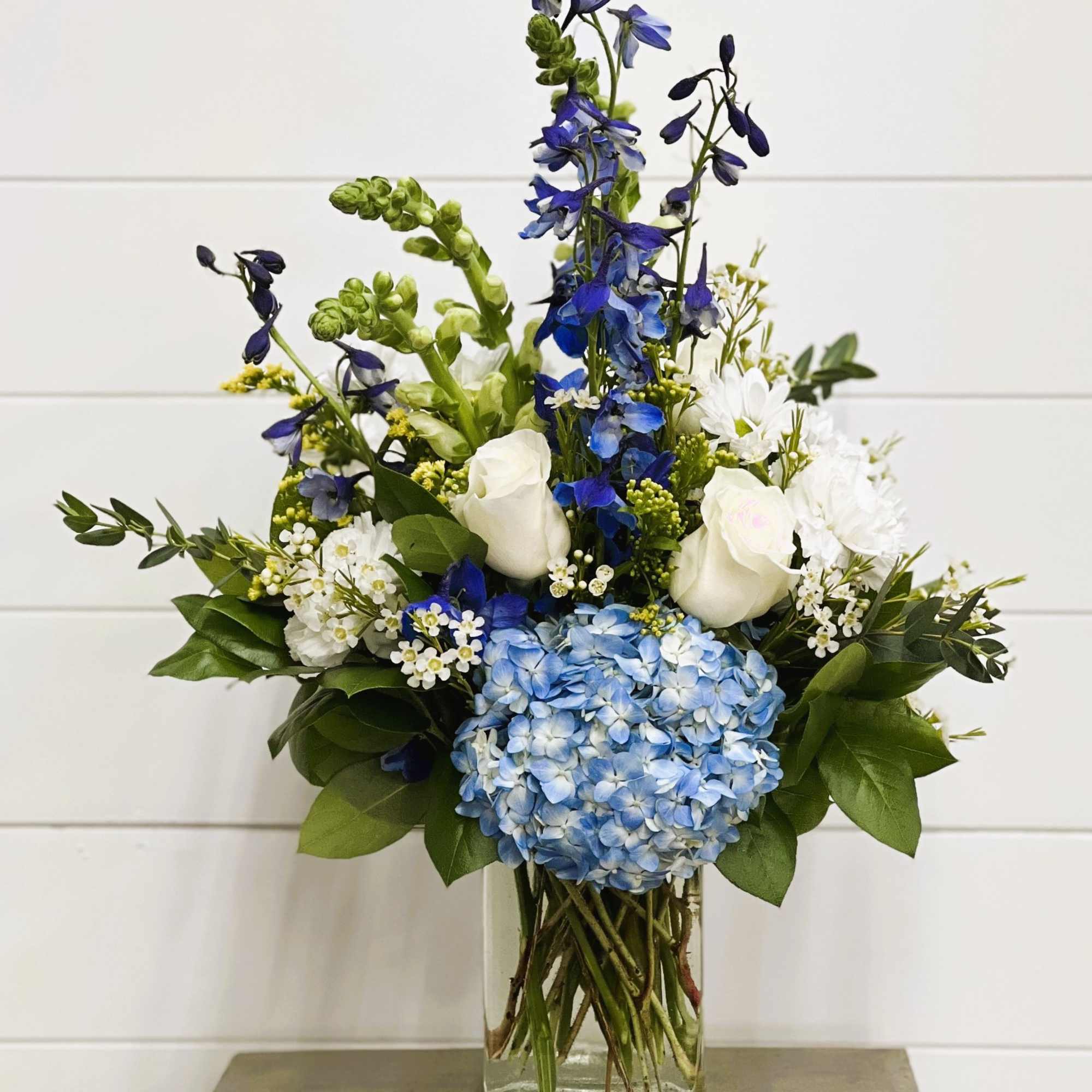 Blue and white floral arrangement in a clear glass vase