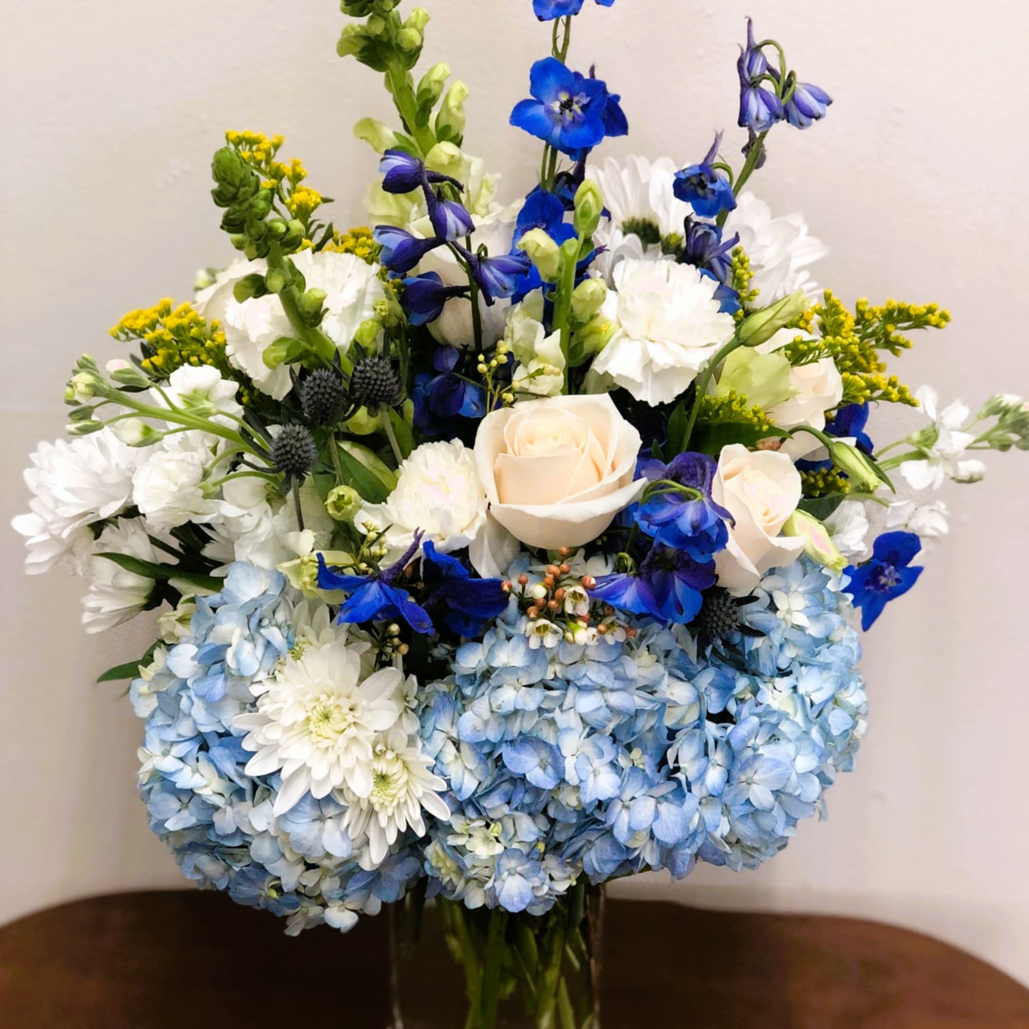 Blue hydrangea and white flower bouquet in a clear glass vase