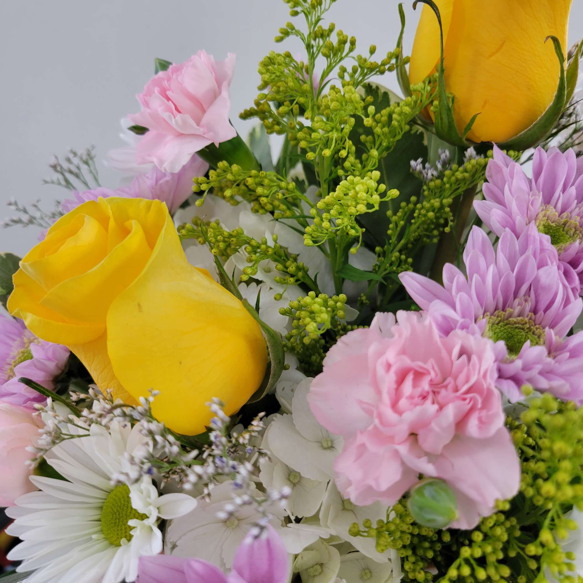 Bouquet of yellow roses, pink carnations, and purple daisies