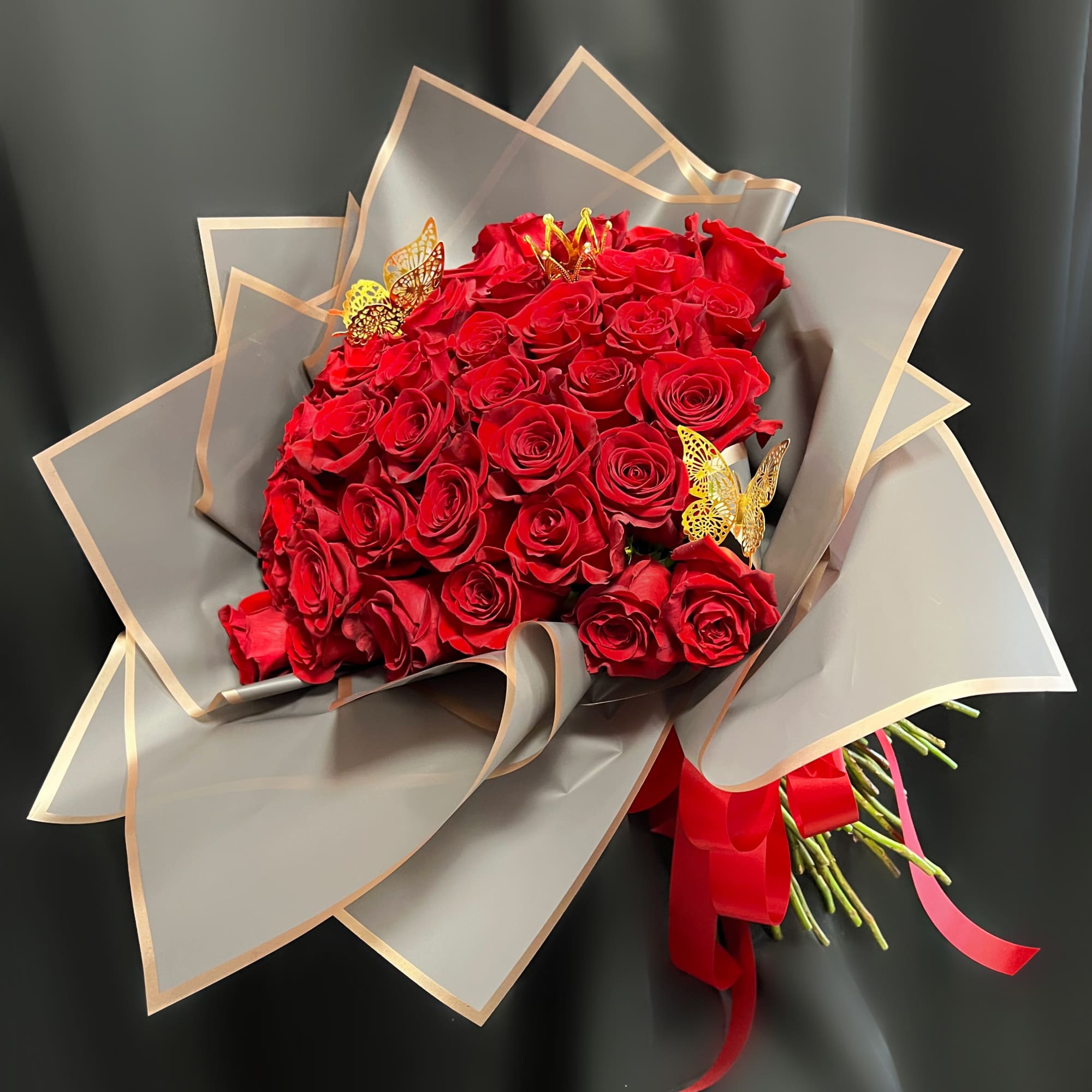 Bouquet of red roses wrapped in gray paper with gold trim