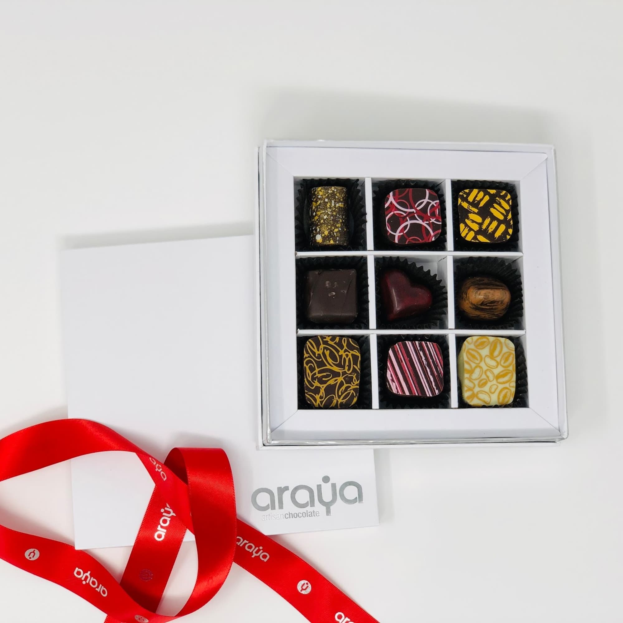 Box of assorted chocolates with a red ribbon and card
