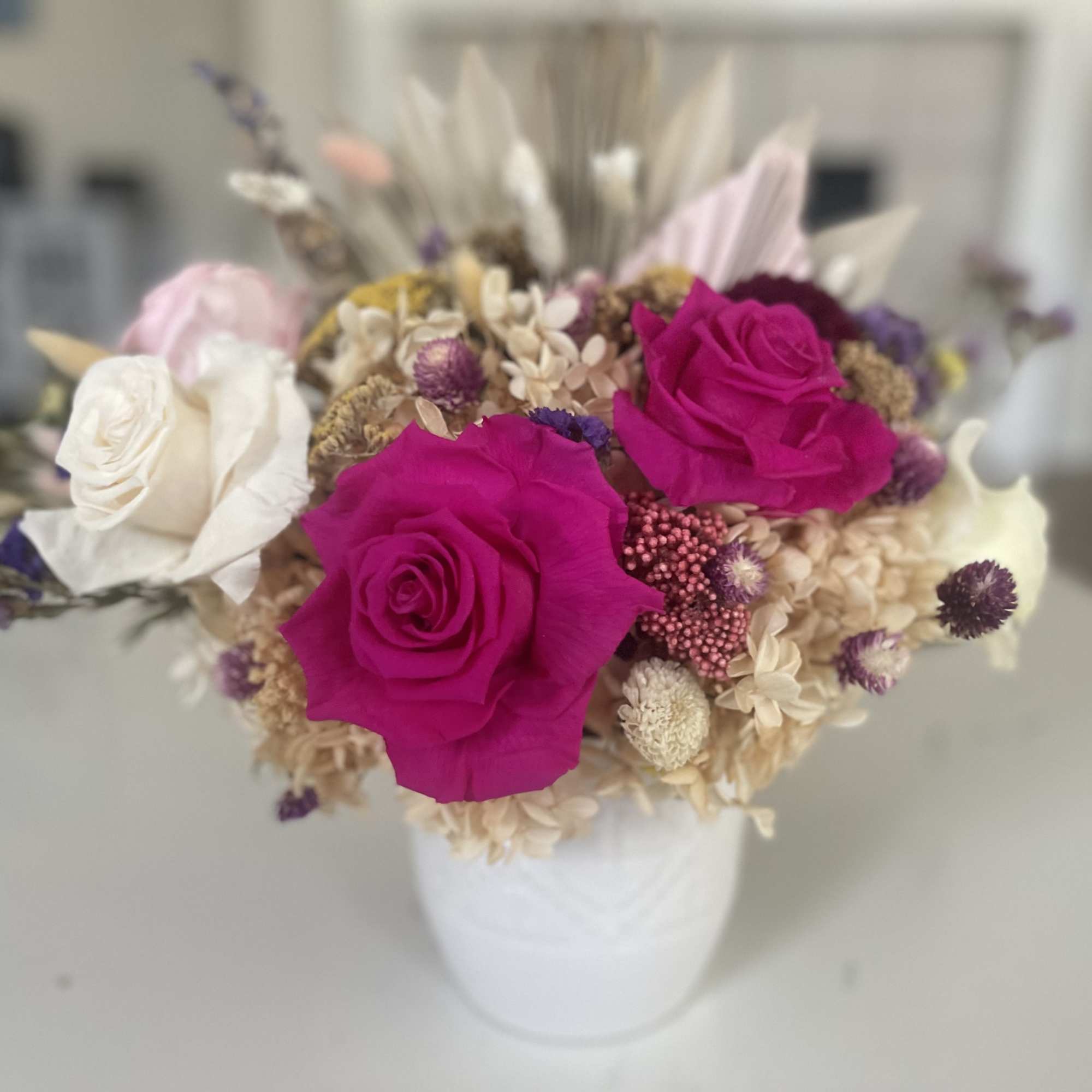 Pink and white roses in a white vase with dried filler flowers