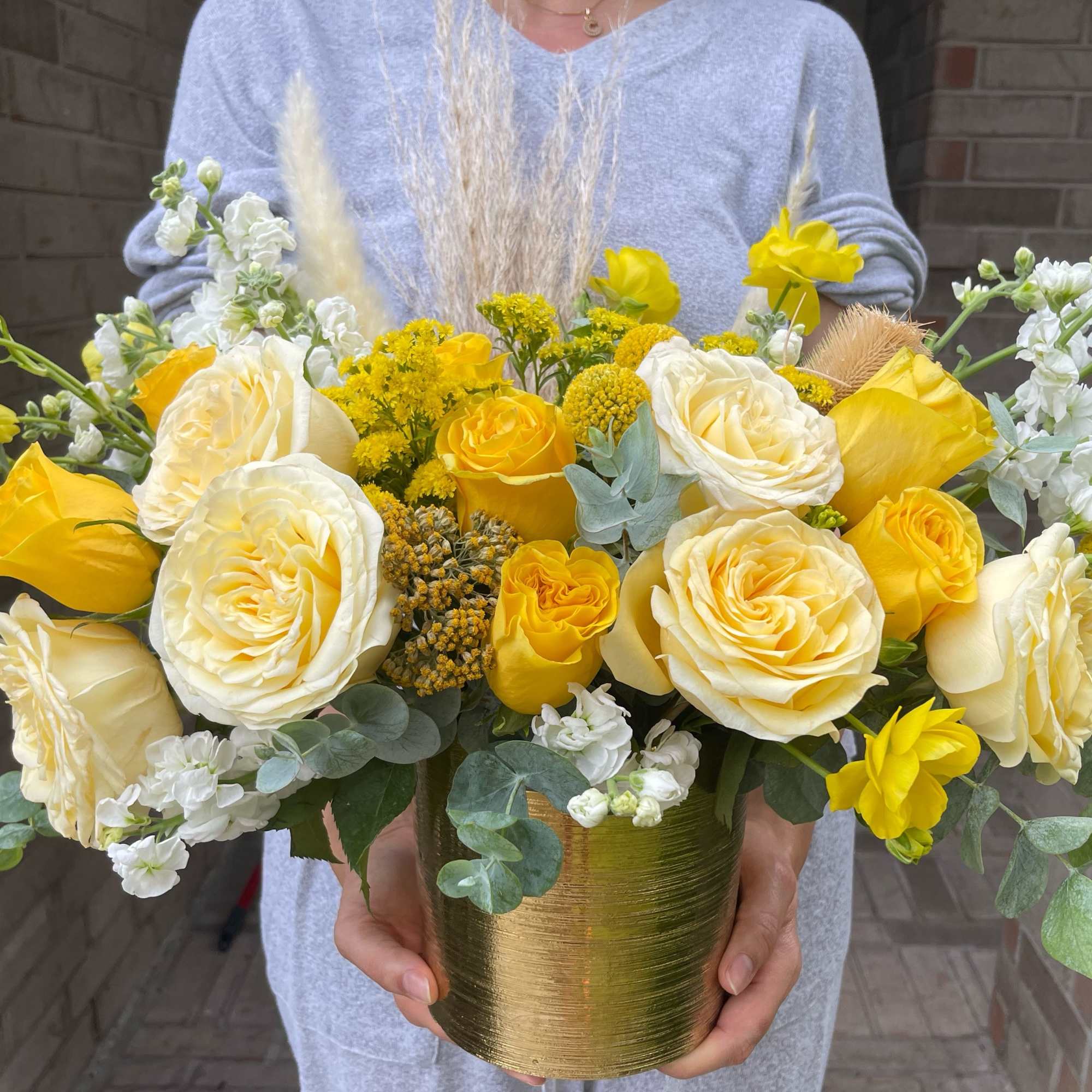 Yellow and white roses arranged in a gold vase