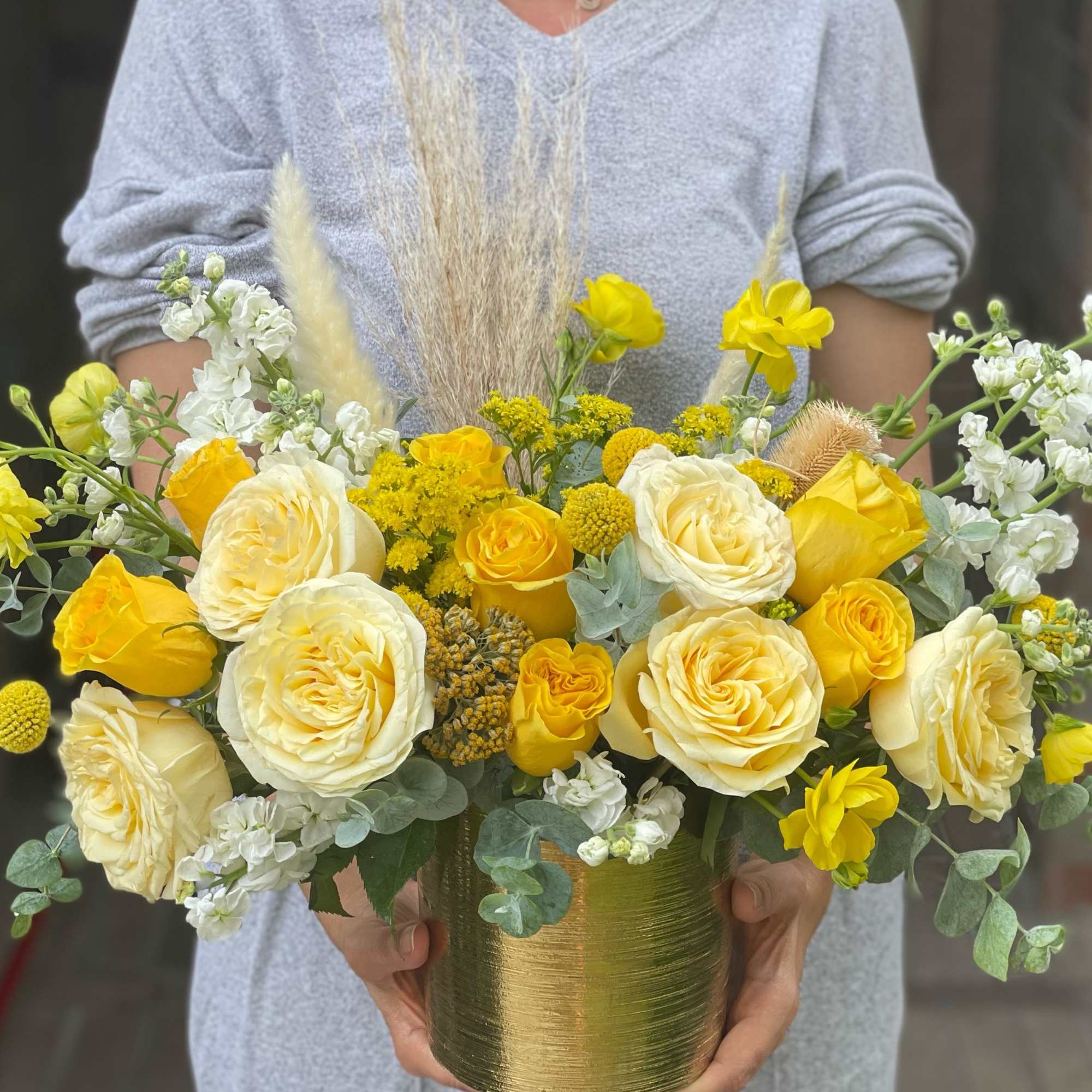 Yellow and white roses in a gold vase with airy filler flowers