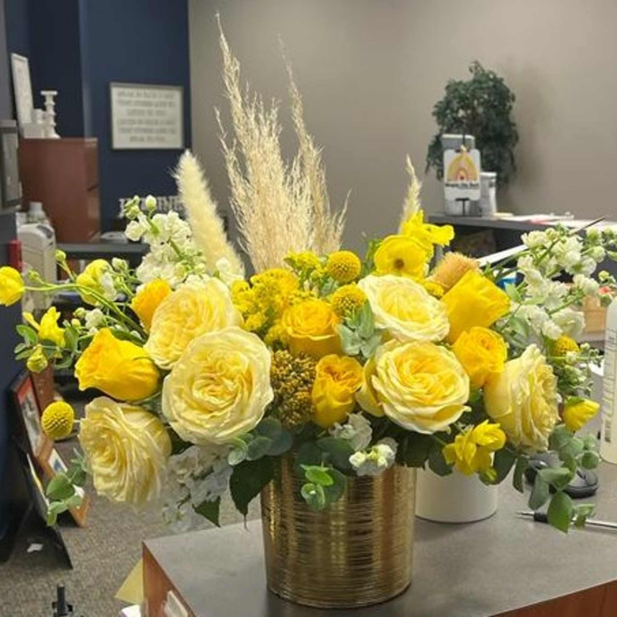 Yellow and white floral arrangement in a gold vase