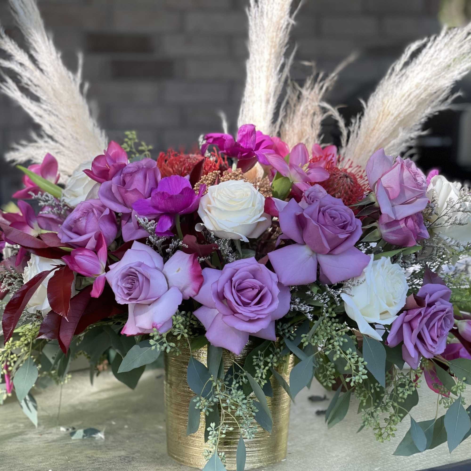 Lavender and white rose arrangement in a gold vase with pampas grass