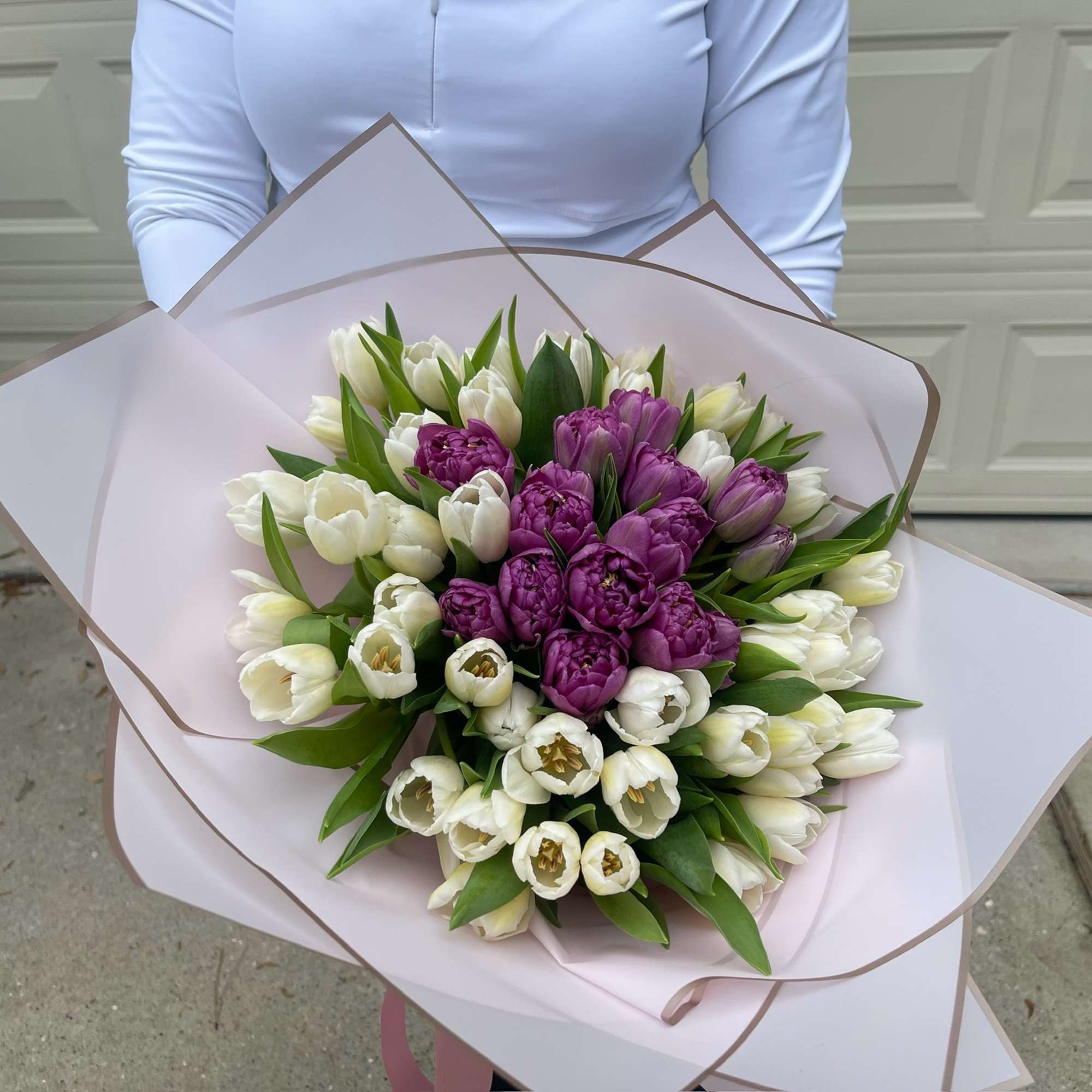 Bouquet of white and purple tulips wrapped in pale pink paper