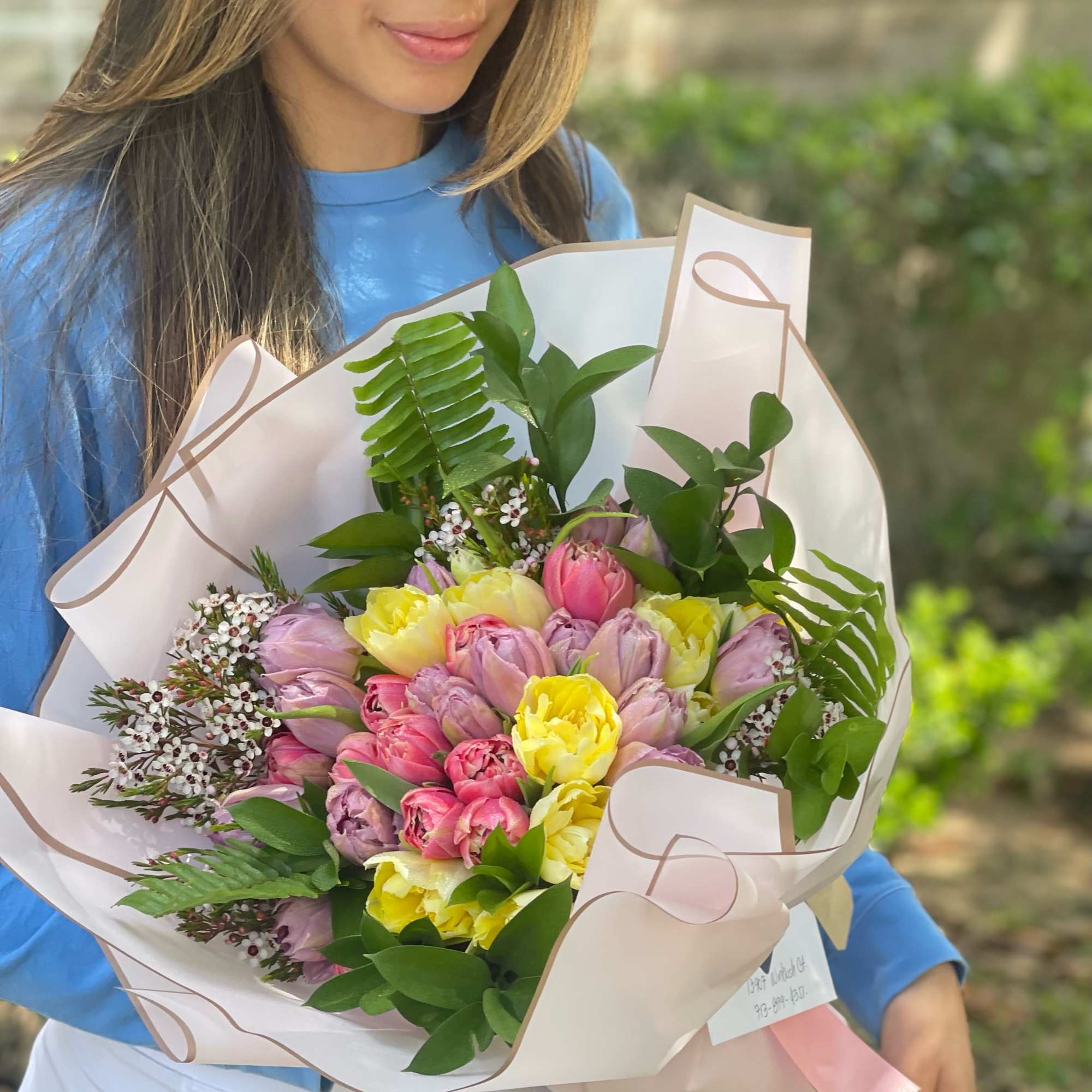 Woman holding a pastel bouquet of tulips wrapped in white paper