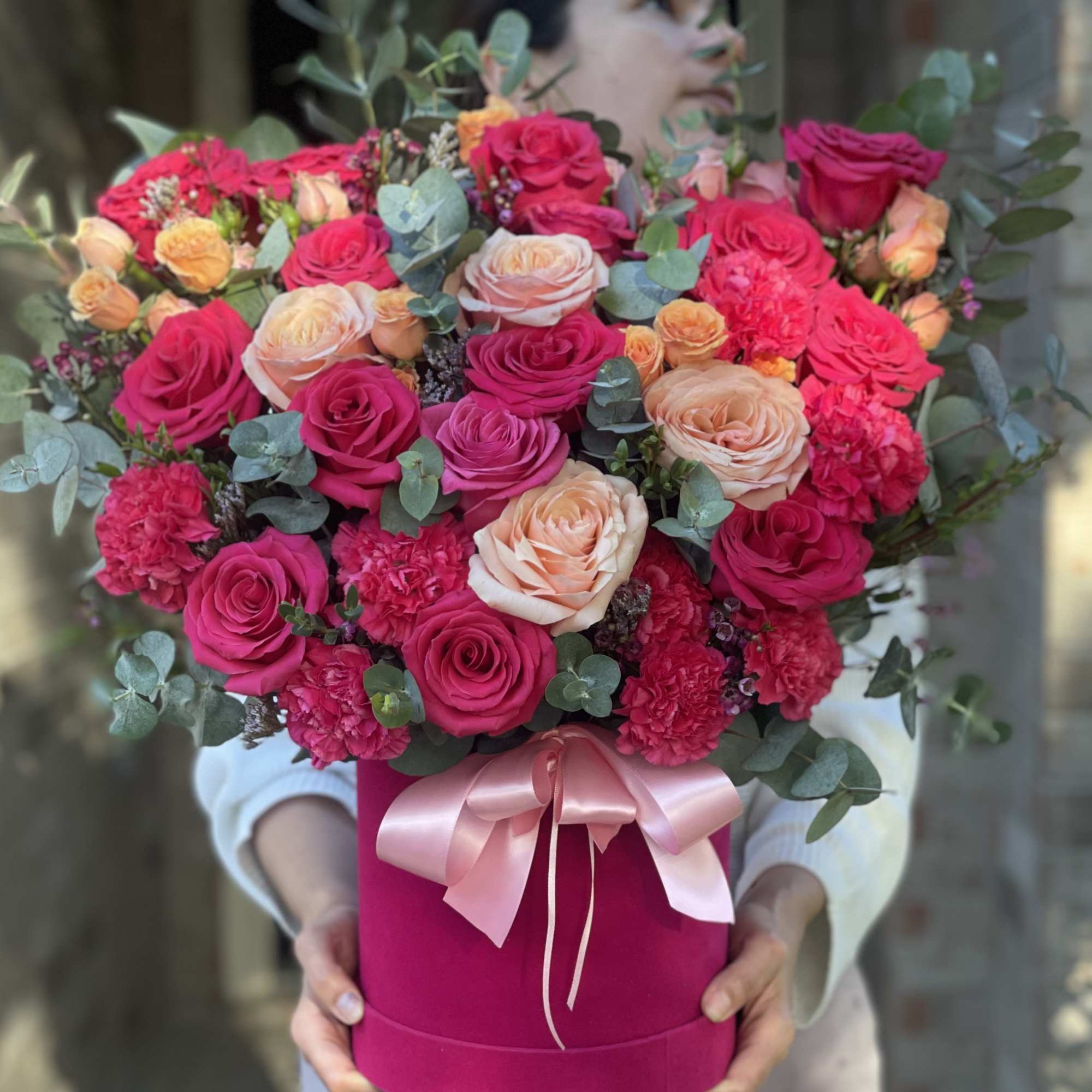 Large bouquet of pink and peach roses in a magenta hat box with a ribbon