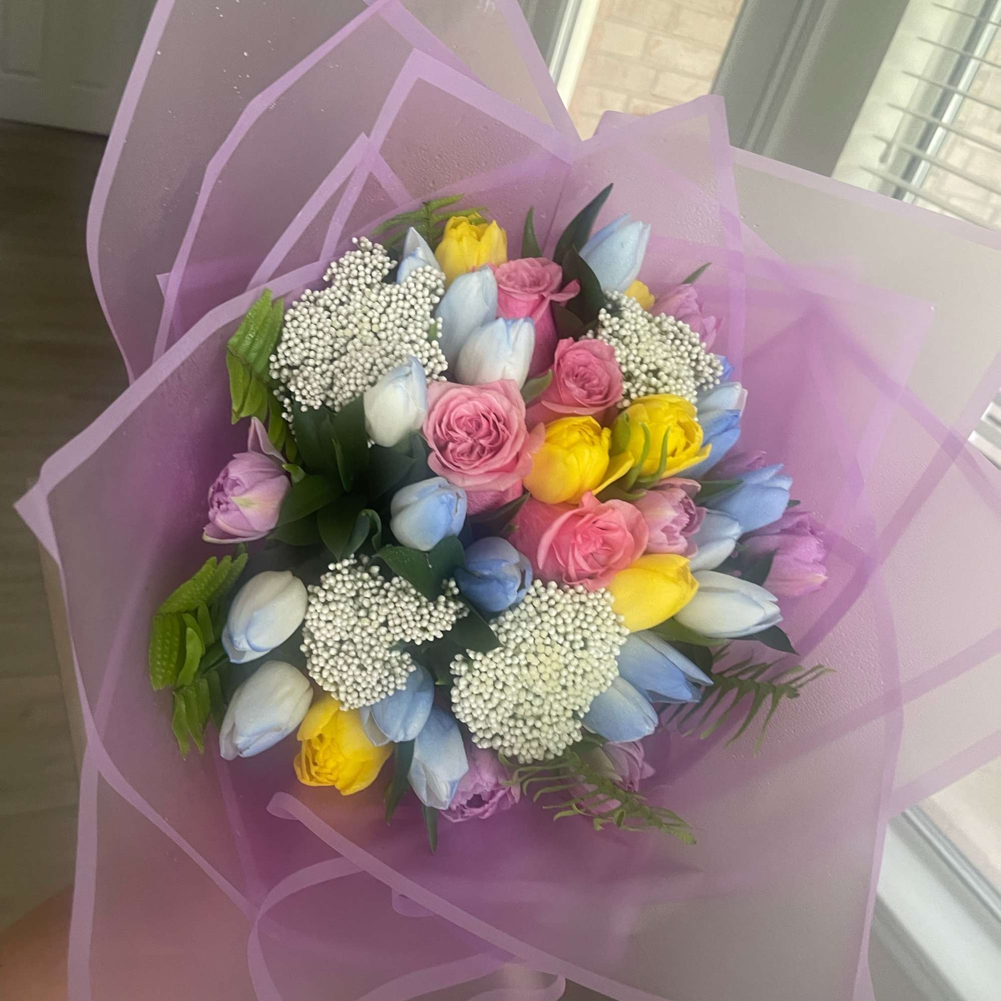 Bouquet of pastel tulips and pink roses wrapped in lavender paper