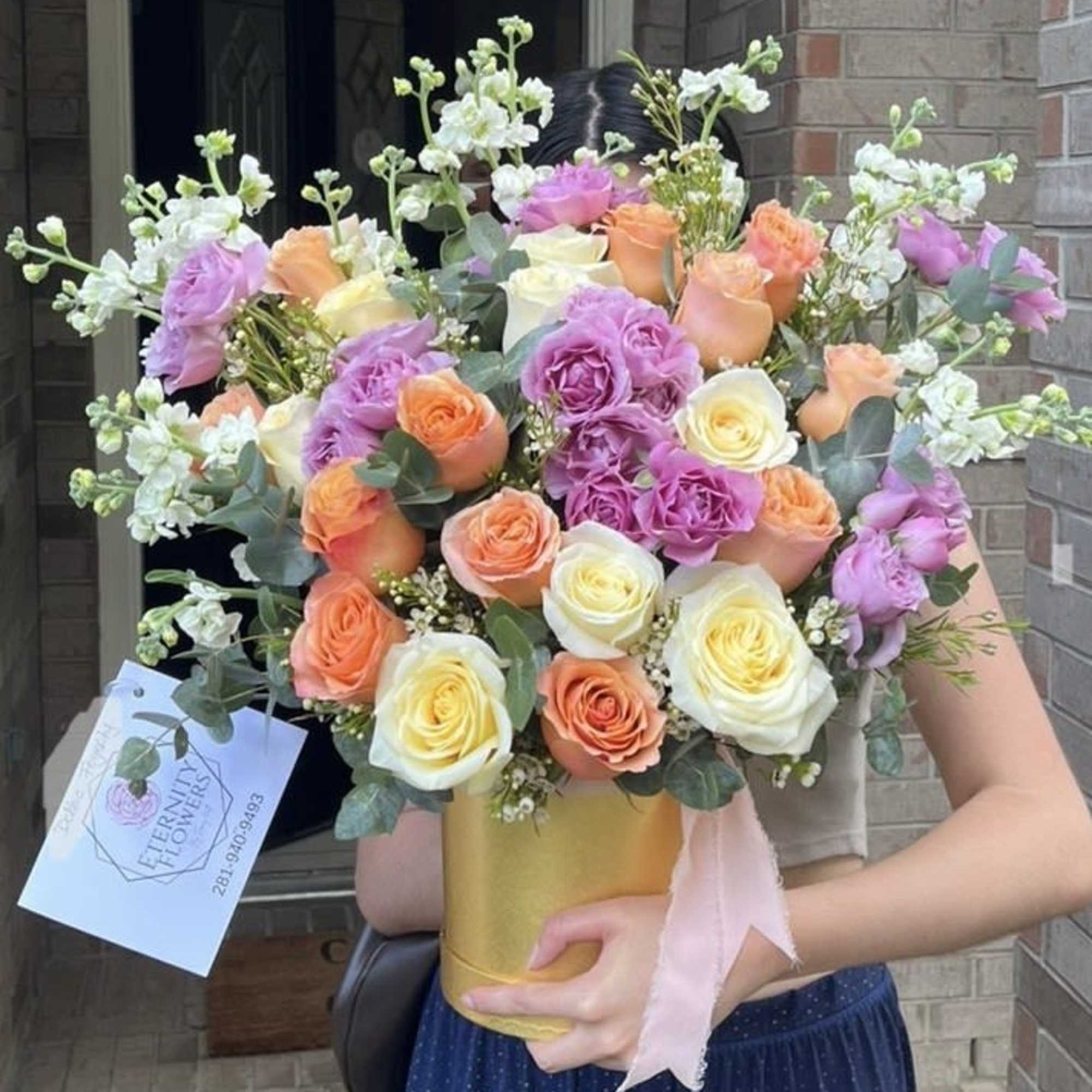 Bouquet of peach, lavender, and white roses in a gold vase