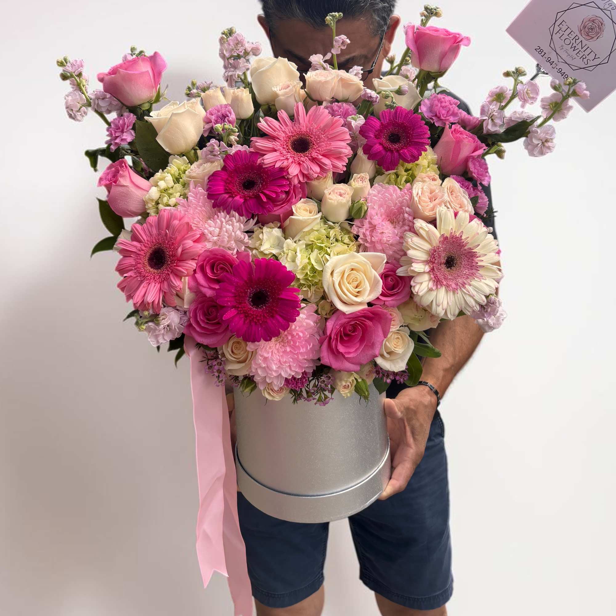 Large pink and cream flower arrangement in a silver hatbox with ribbon