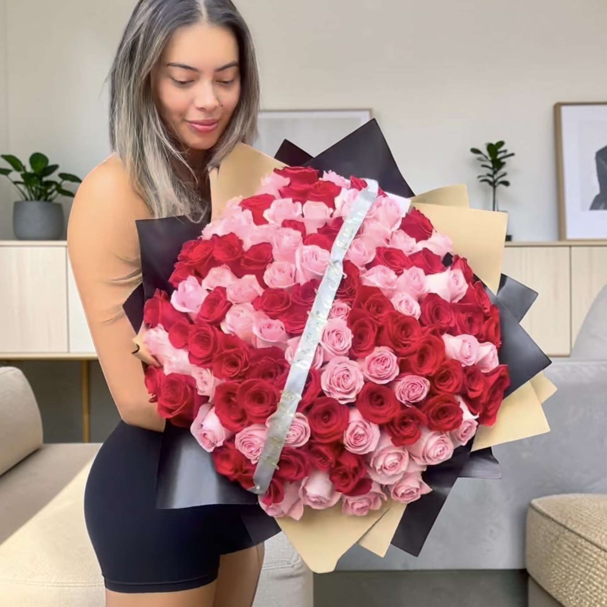 Large bouquet of red and pink roses wrapped in black and beige paper