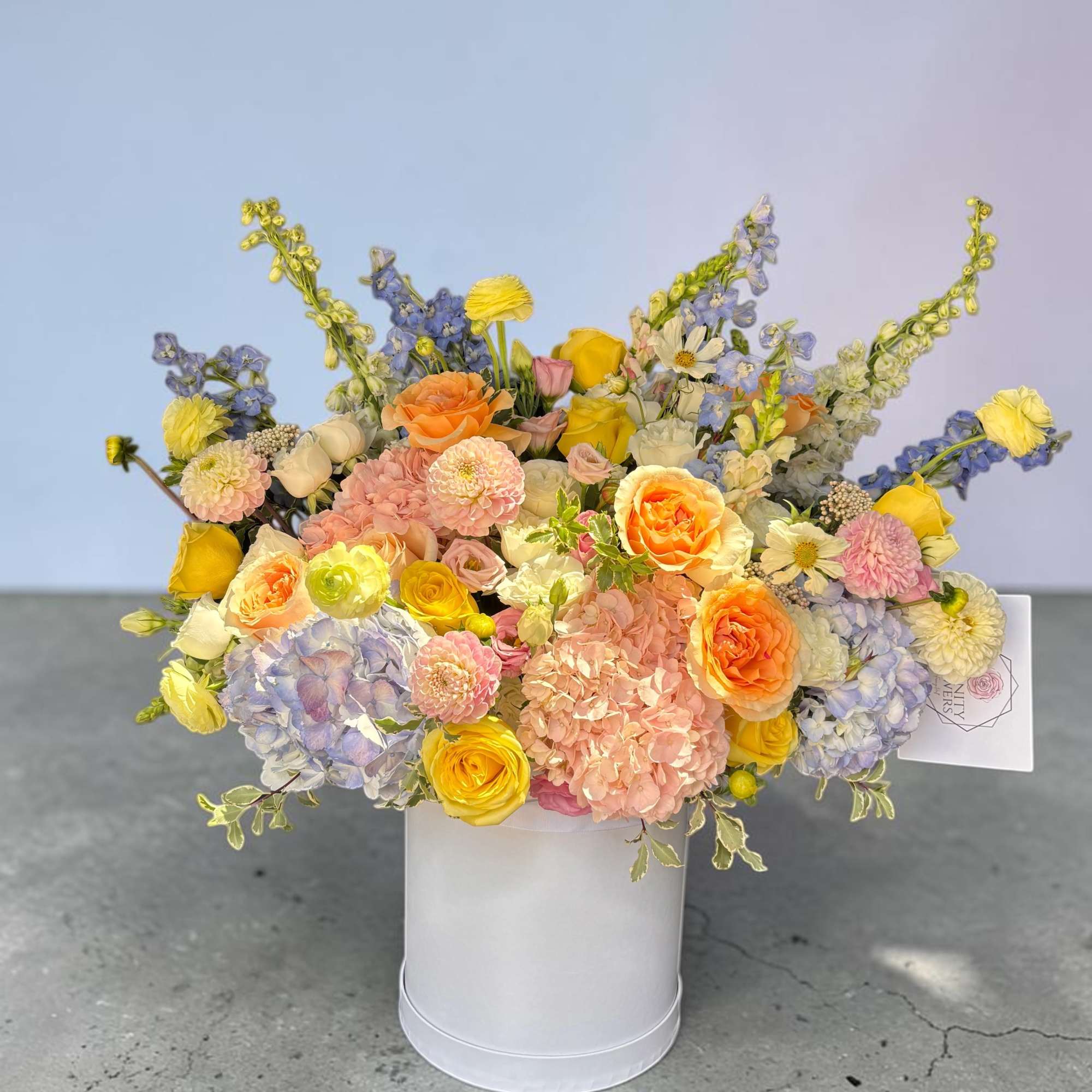 Mixed pastel bouquet in a white hatbox with roses and hydrangeas
