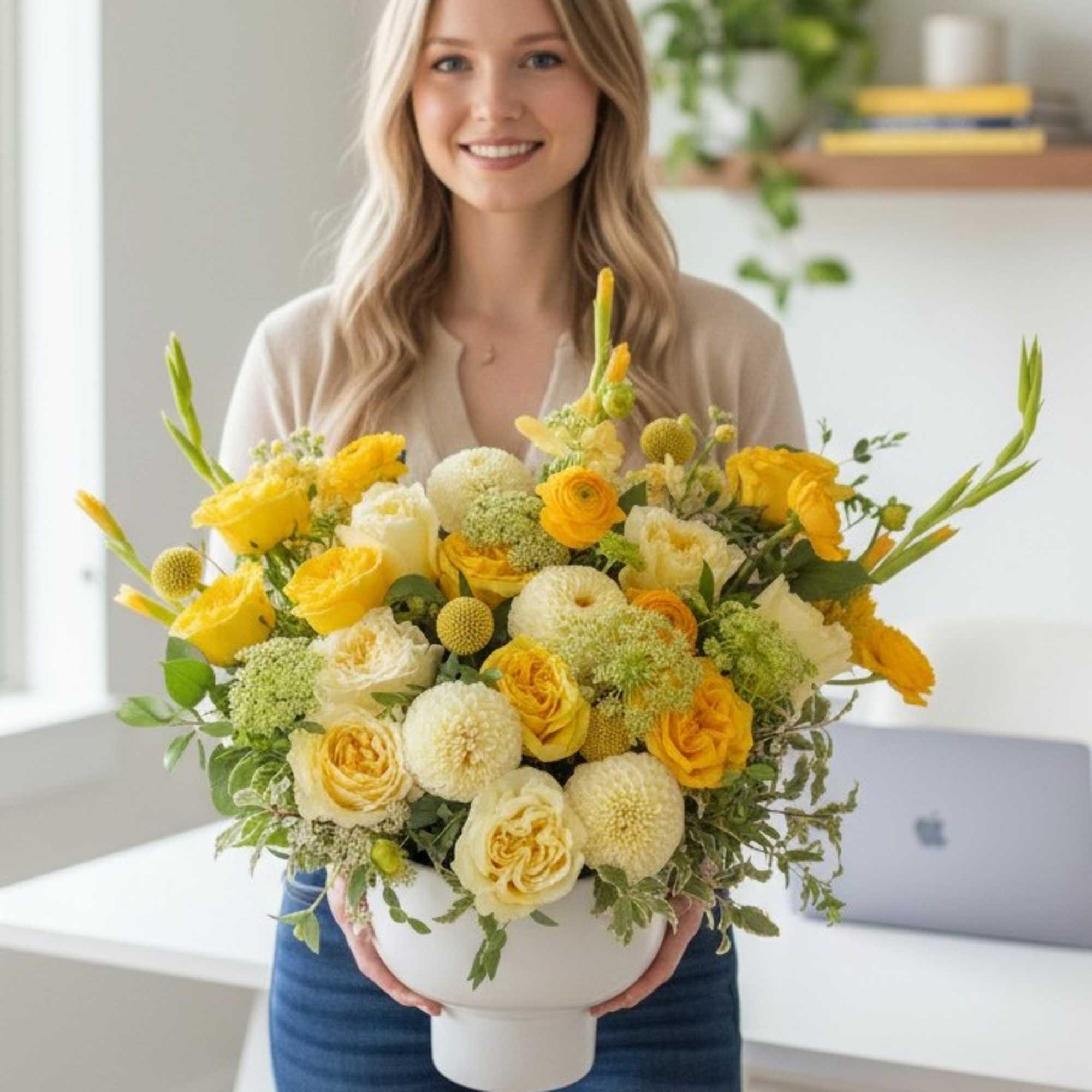 Woman holding a large yellow and white flower arrangement in a white pedestal vase