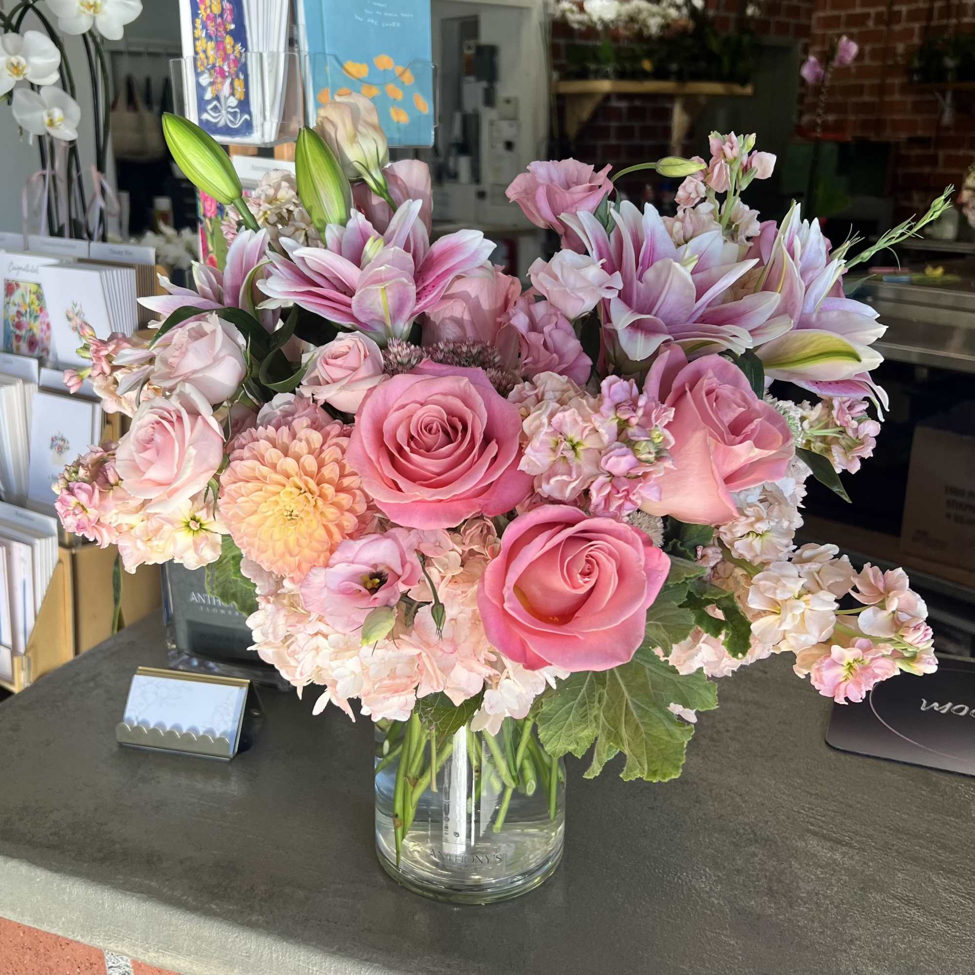 Pink roses and lilies arranged in a clear glass vase.