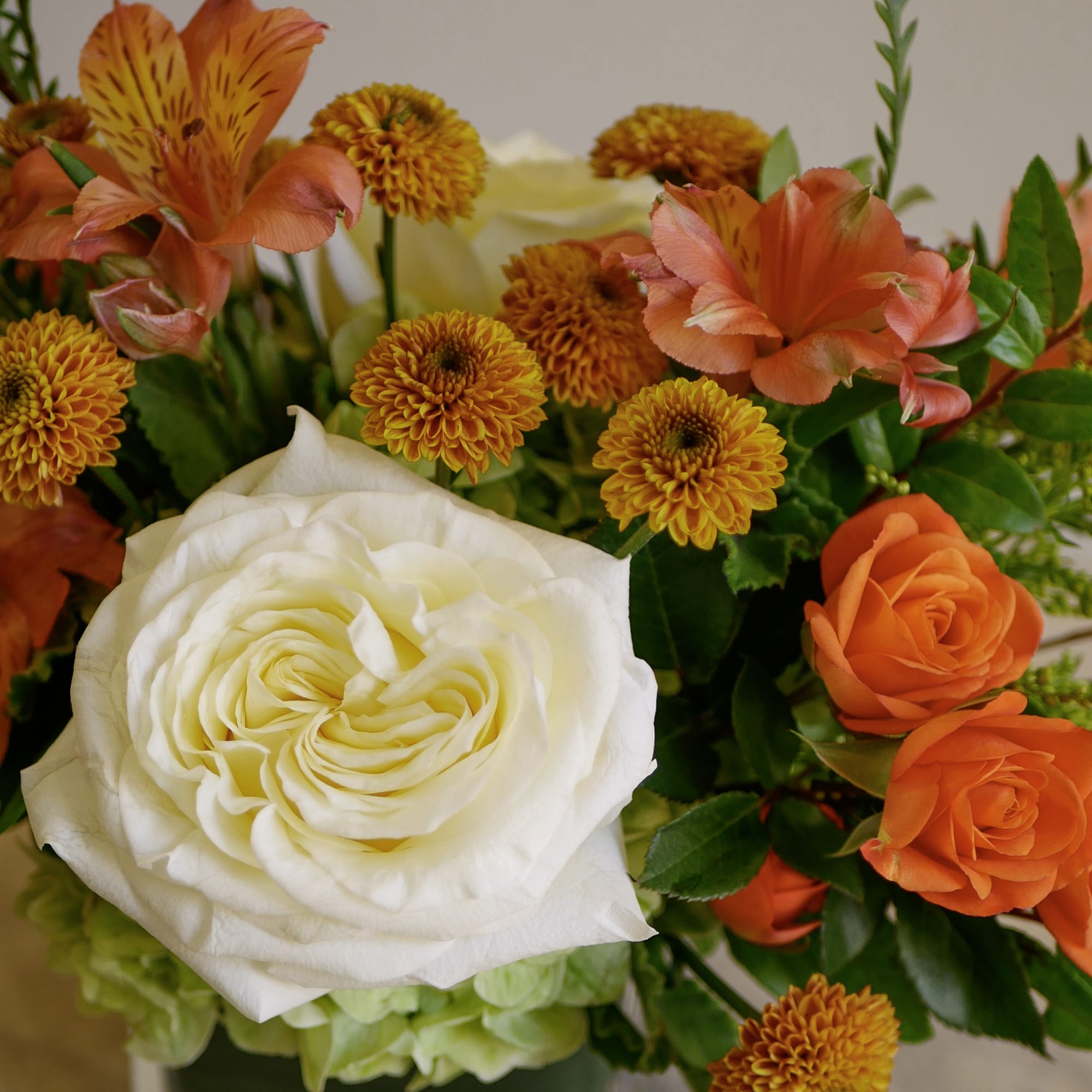 Arrangement of white and orange roses with orange mums and alstroemeria