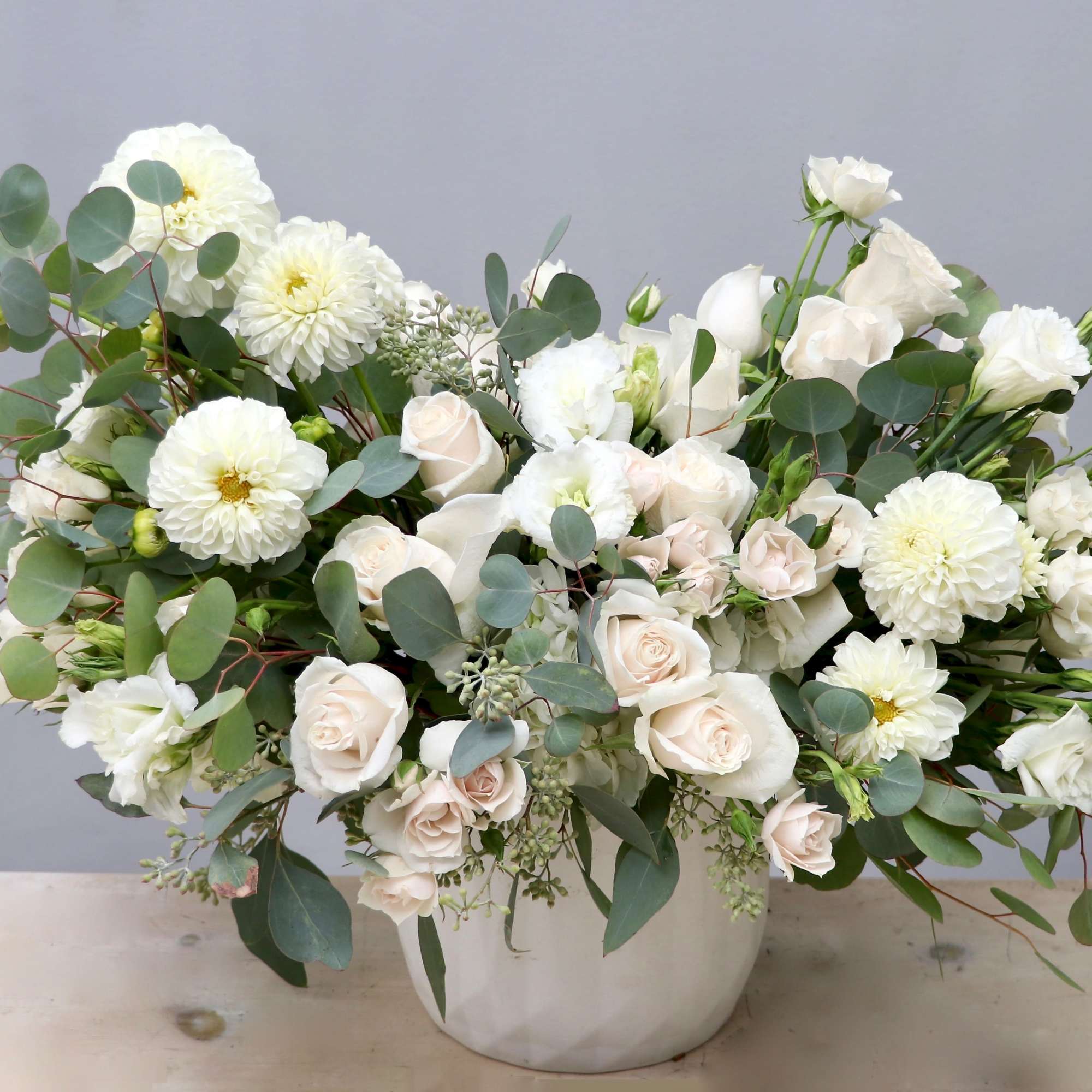 Large white and cream flower arrangement in a white ceramic vase