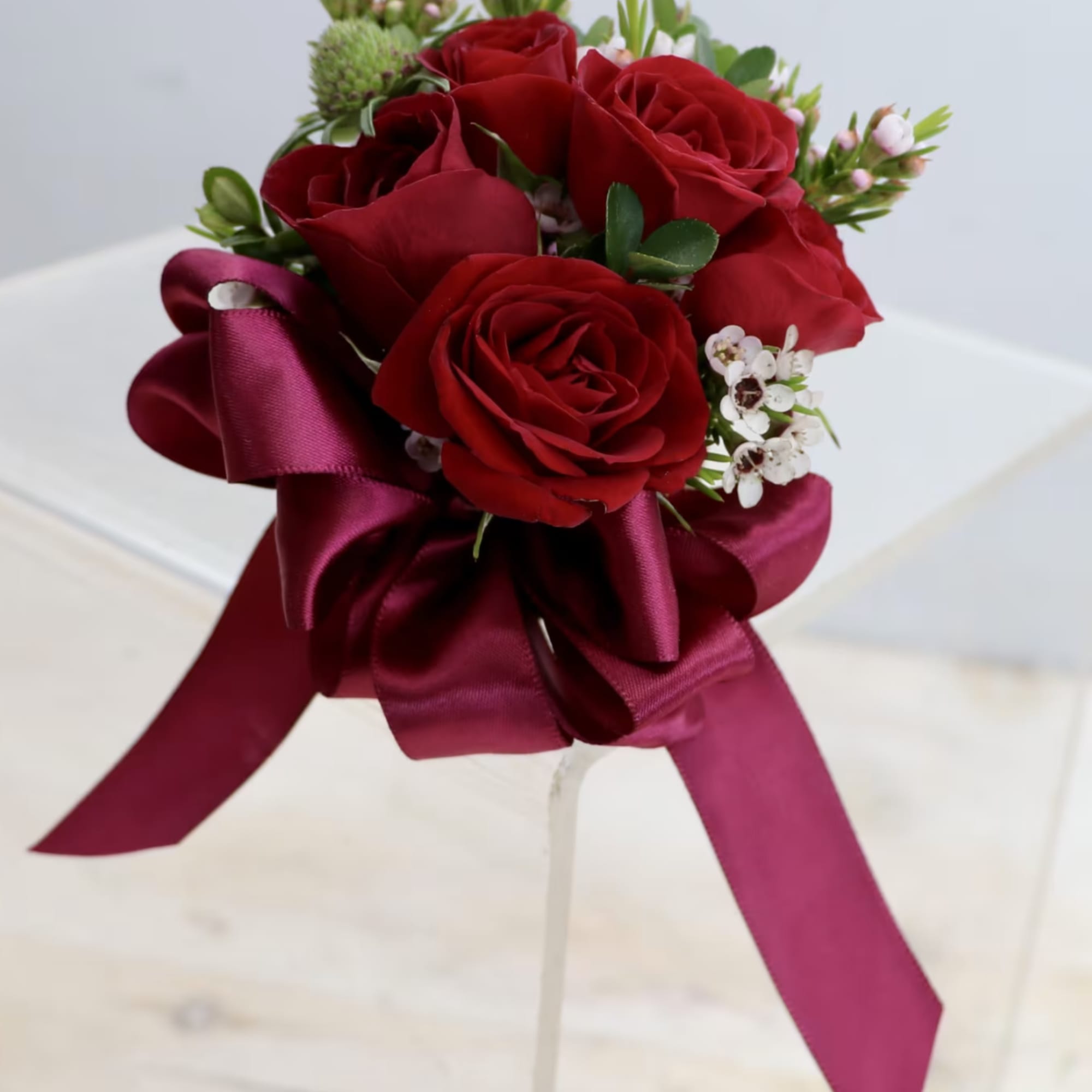 Small bouquet of red roses with white filler flowers and a deep red satin bow