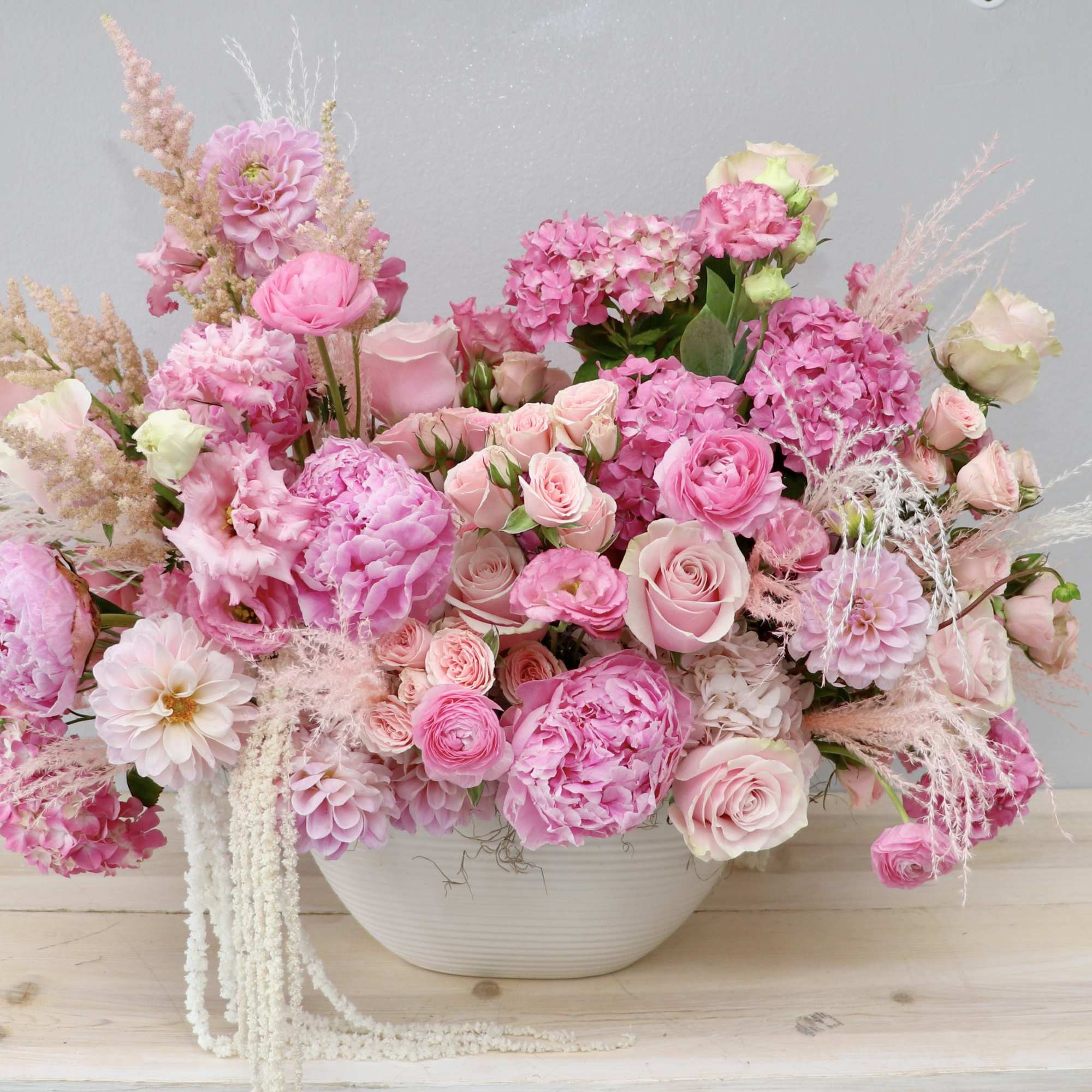 Pink floral arrangement in a white bowl vase