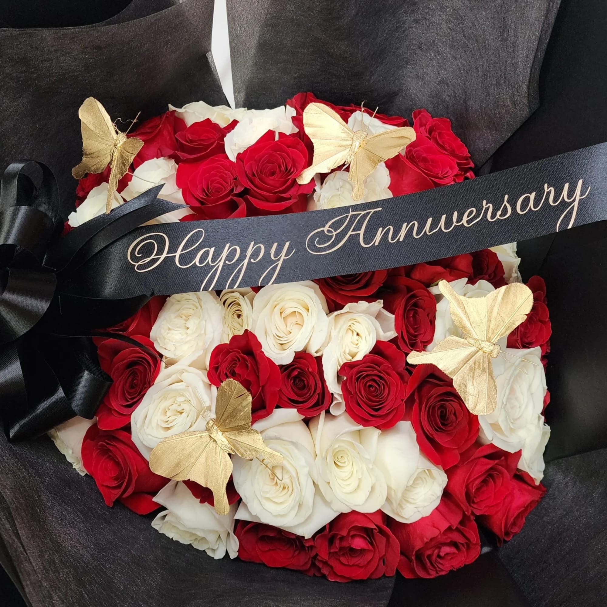 Red and white rose bouquet with gold butterflies and a Happy Anniversary ribbon