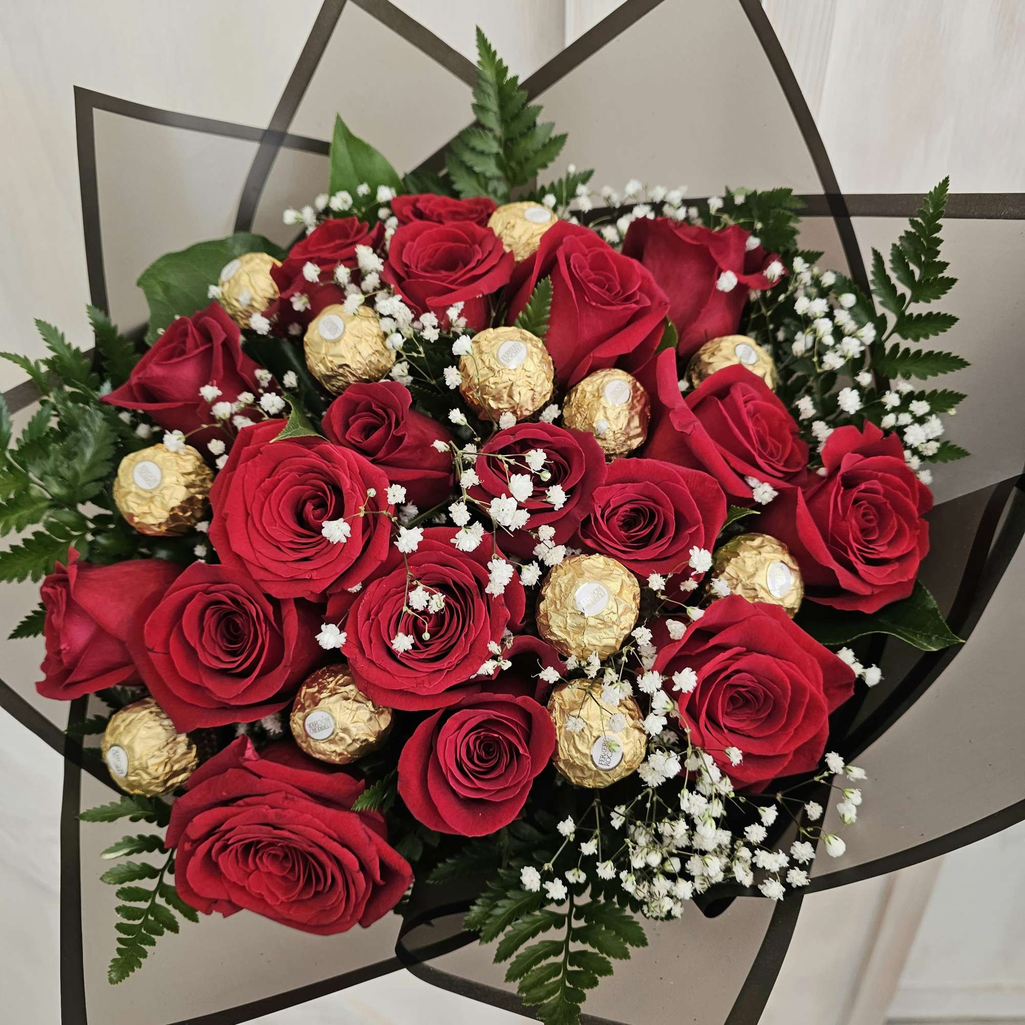 Bouquet of red roses with gold-wrapped chocolates and baby's breath