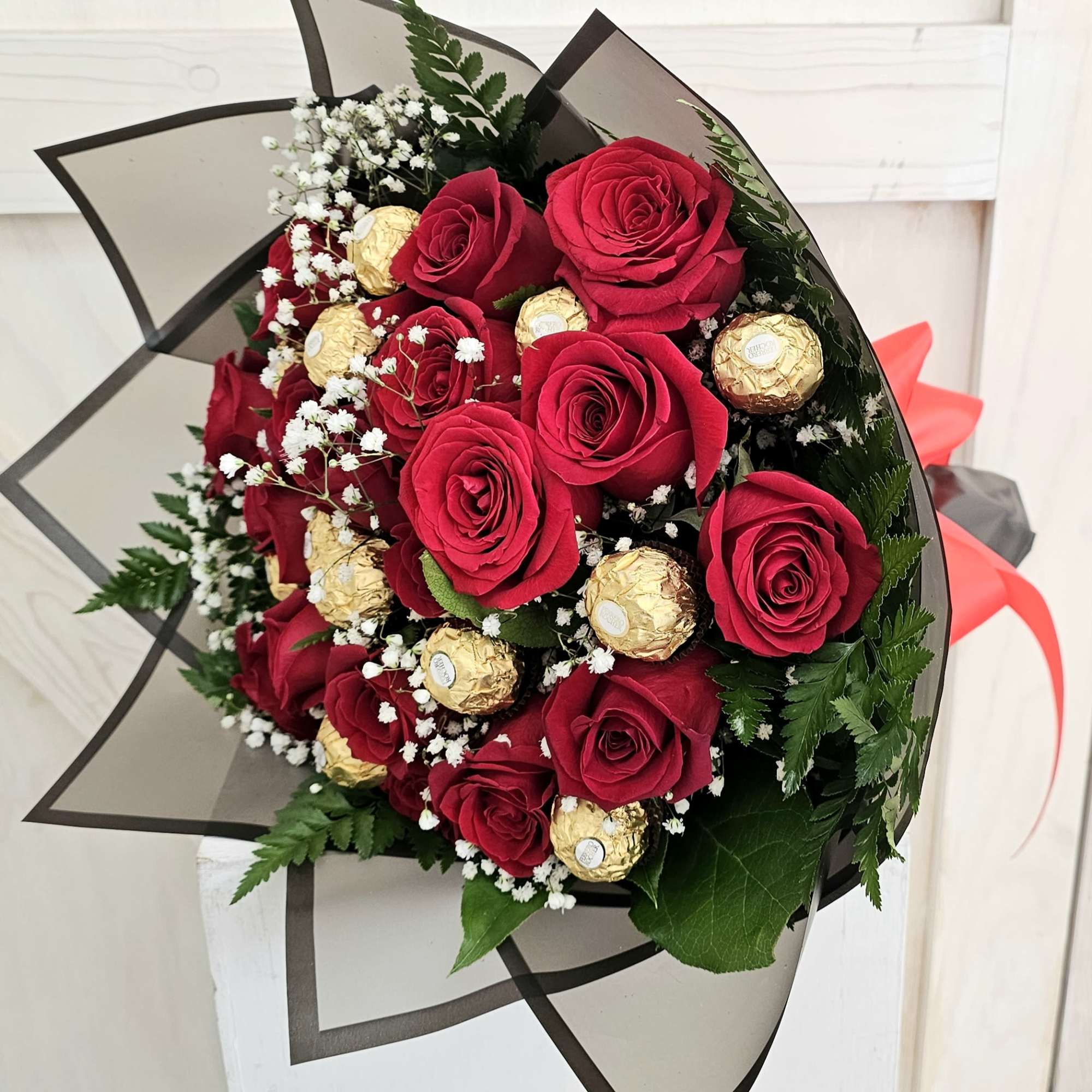 Bouquet of red roses with gold-wrapped chocolates and white baby's breath