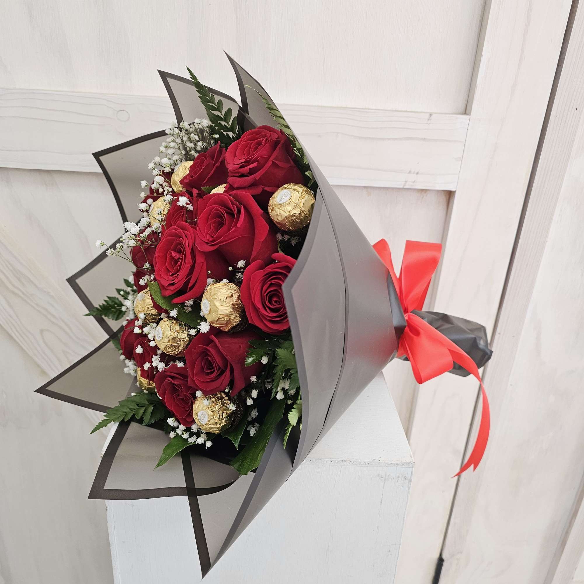 Bouquet of red roses with gold-wrapped chocolates and white filler flowers