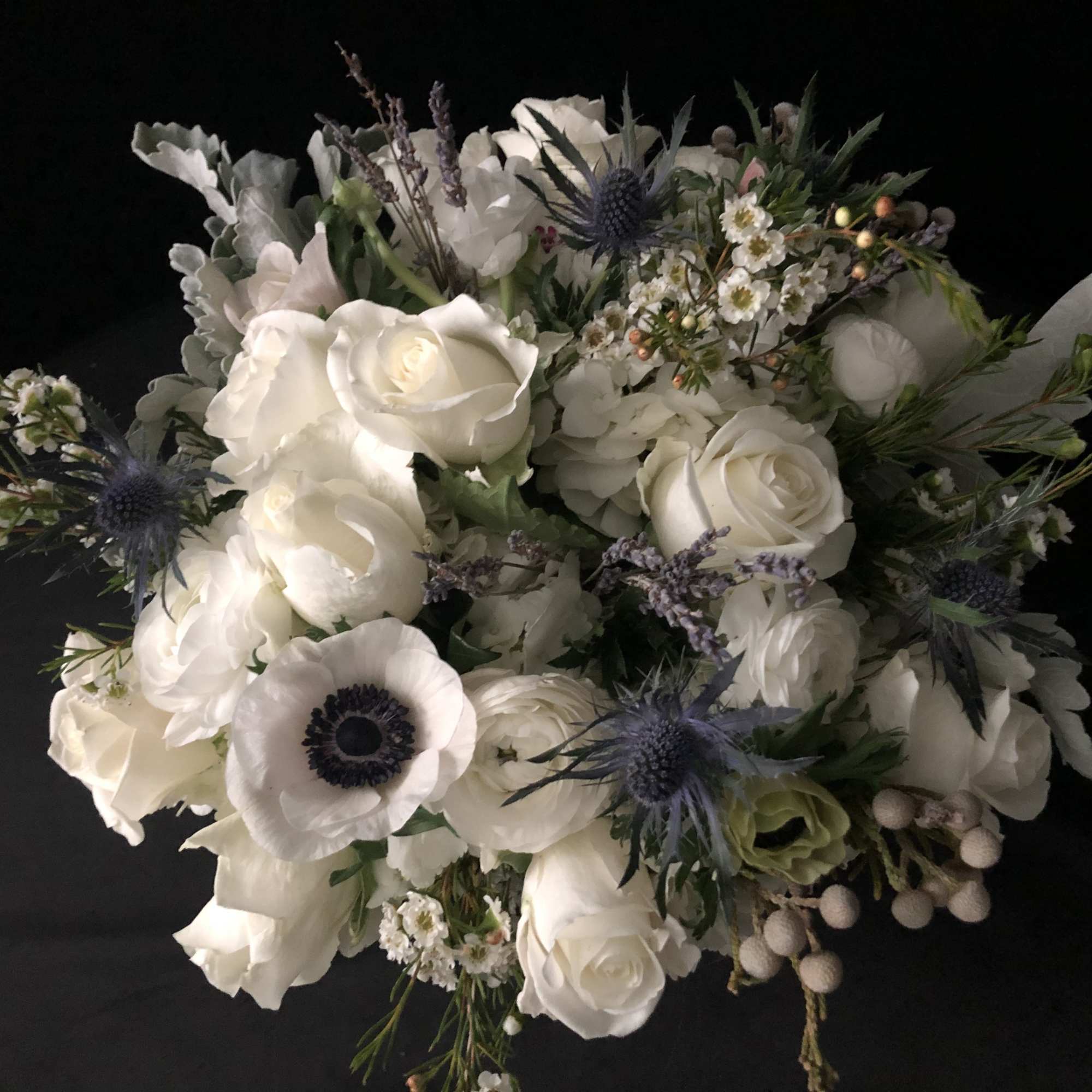 White rose bouquet with blue thistle and small white filler flowers