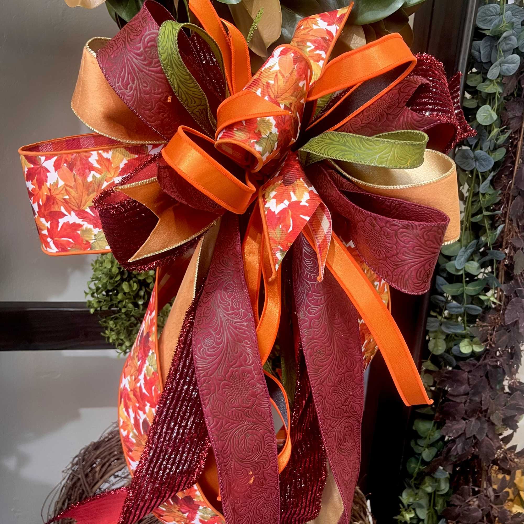 Large decorative bow in red, orange, gold, and green ribbon
