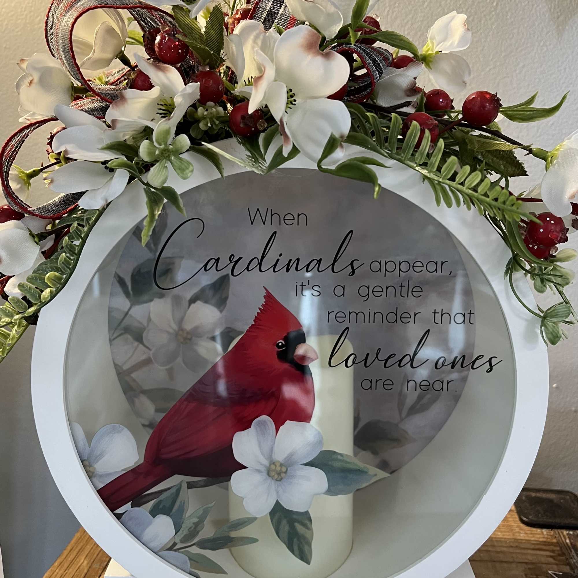 White floral wreath with red berries around a cardinal memorial sign
