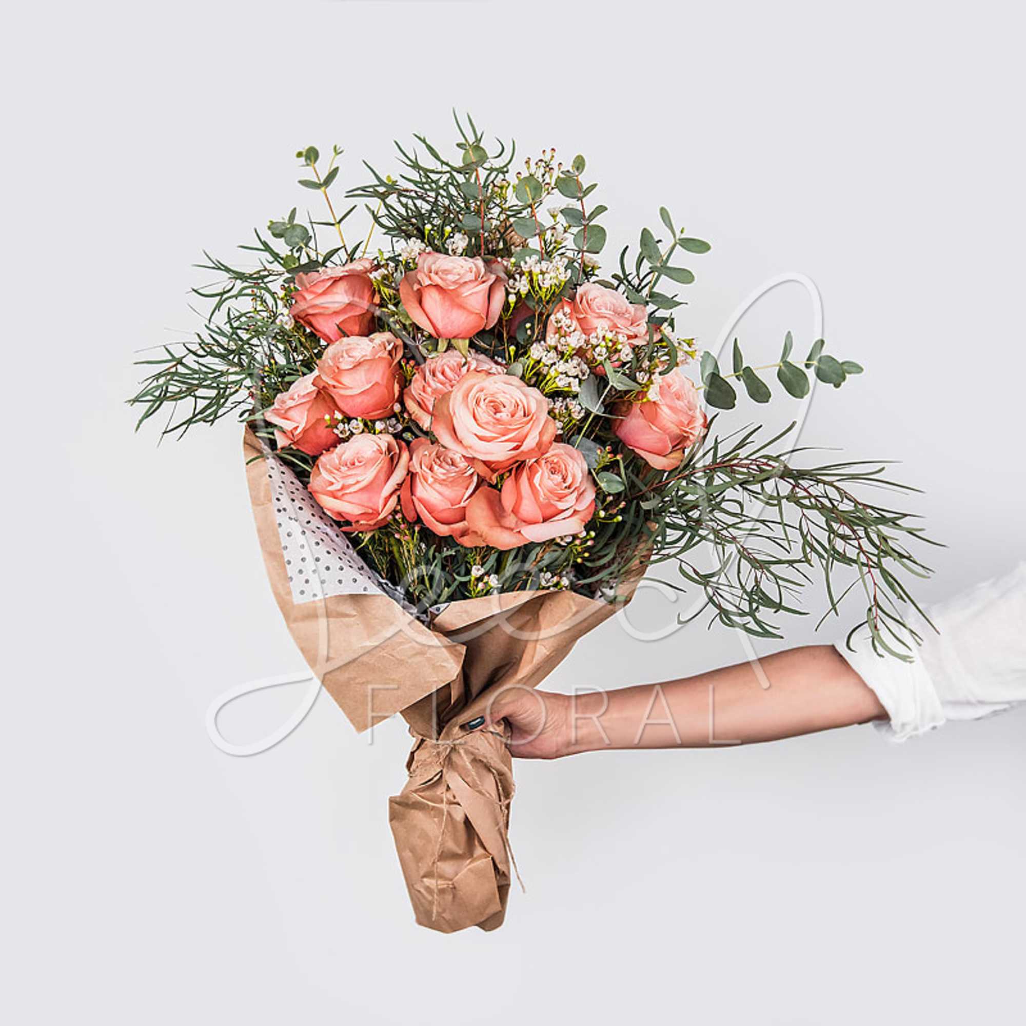 Hand-tied bouquet of peach roses with greenery and small white filler flowers