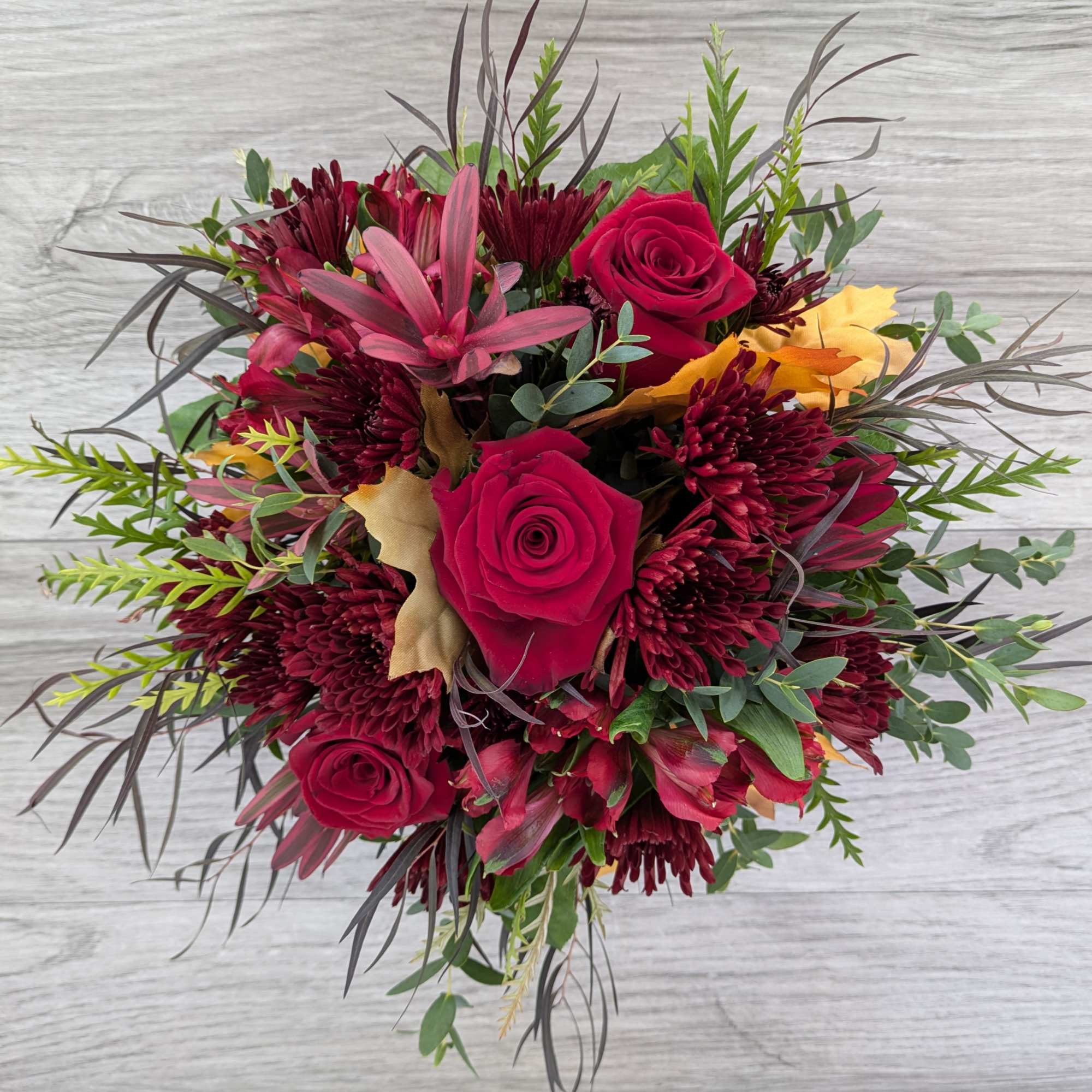 Bouquet of red roses and burgundy chrysanthemums with mixed greenery
