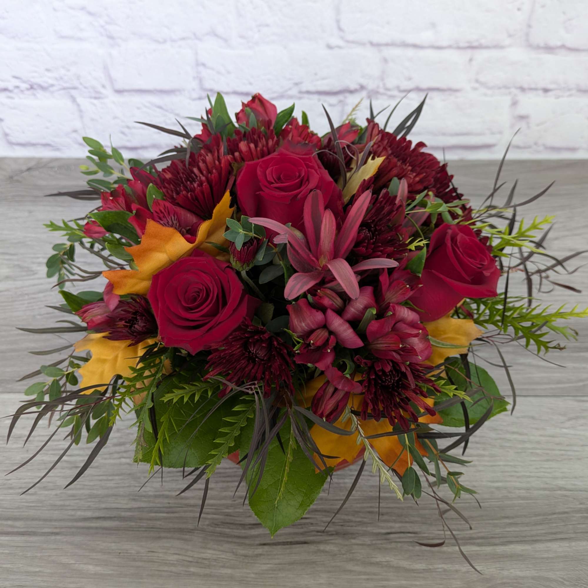 Bouquet of red roses and burgundy flowers with yellow accents