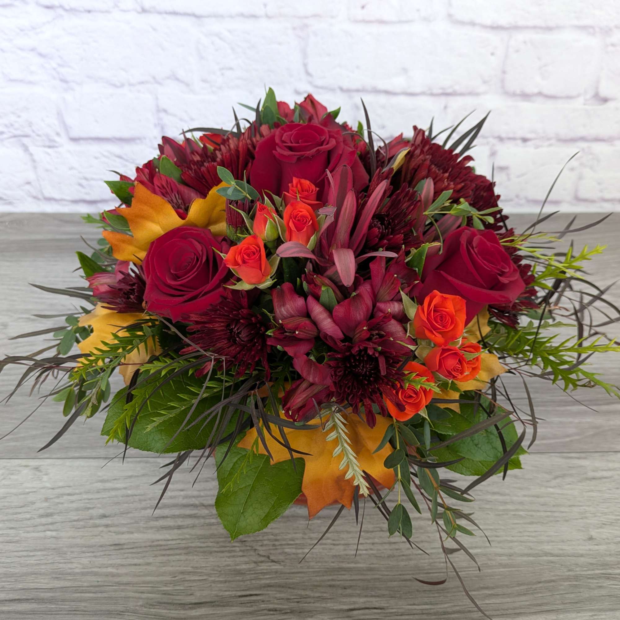 Bouquet of red roses, orange spray roses, and burgundy flowers