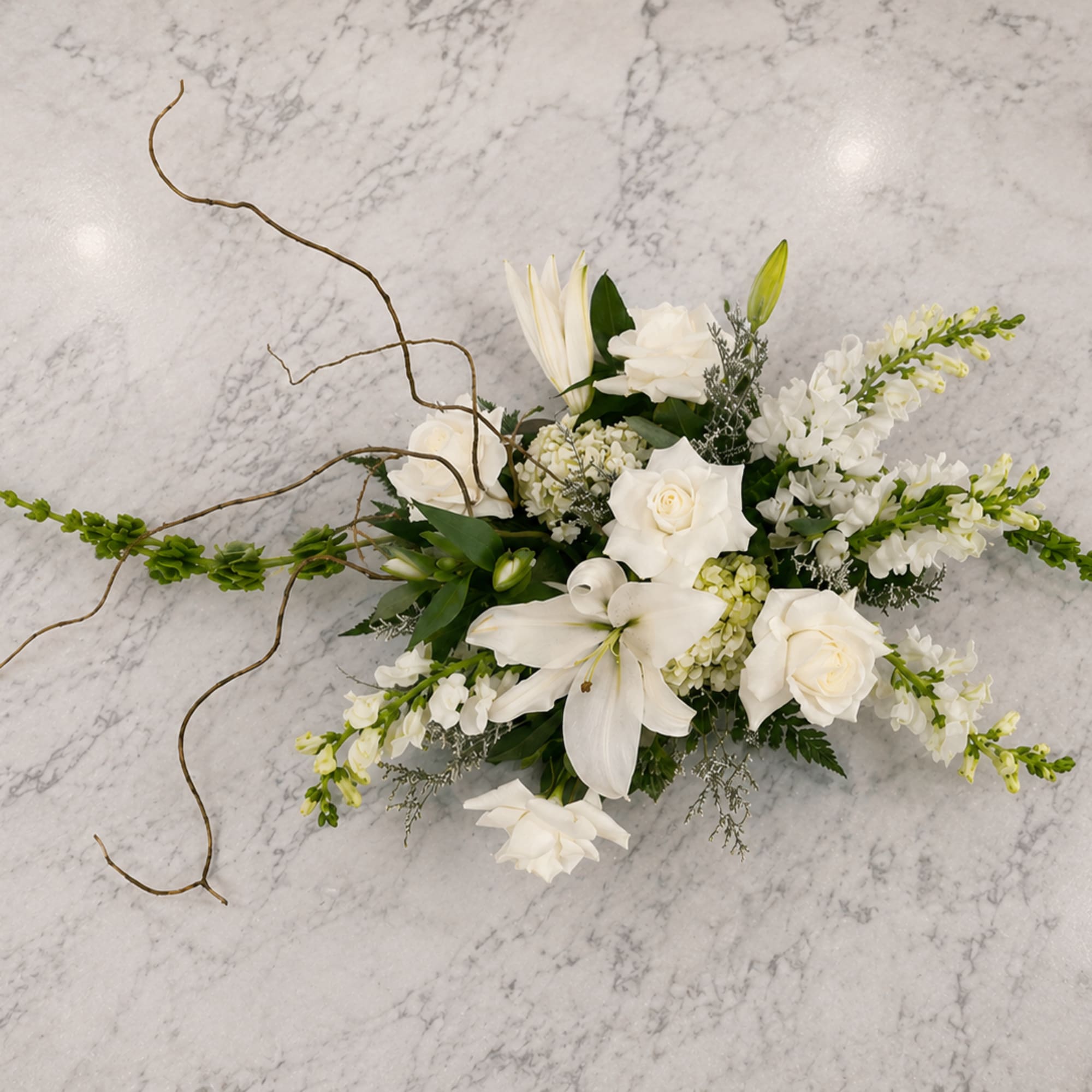 White floral arrangement with lilies and roses on a marble surface