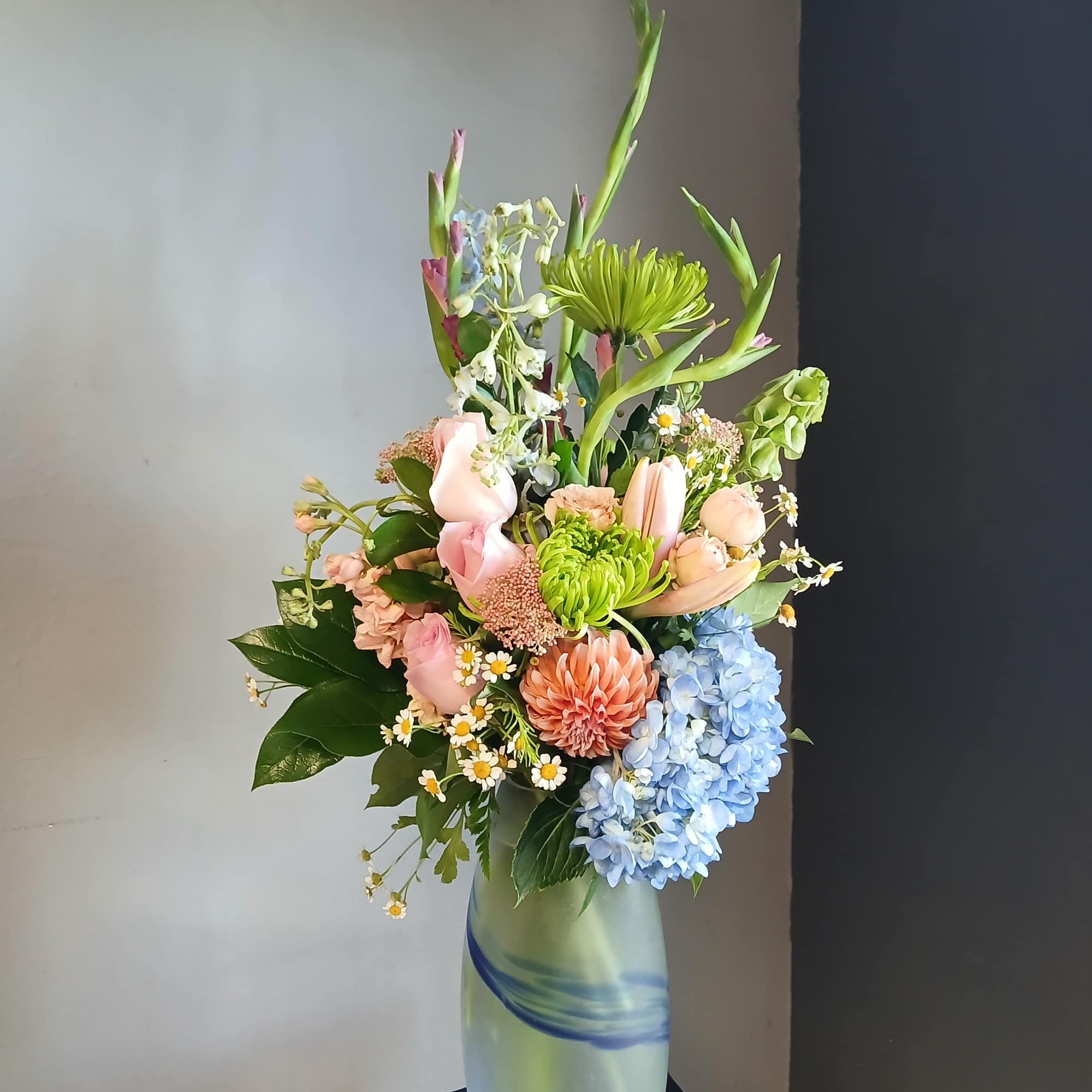 Mixed pastel bouquet in a tall frosted glass vase